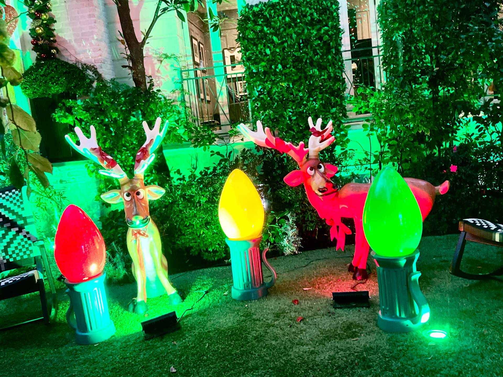Two cartoon reindeer decorations with large antlers and colorful oversized Christmas lights nearby.