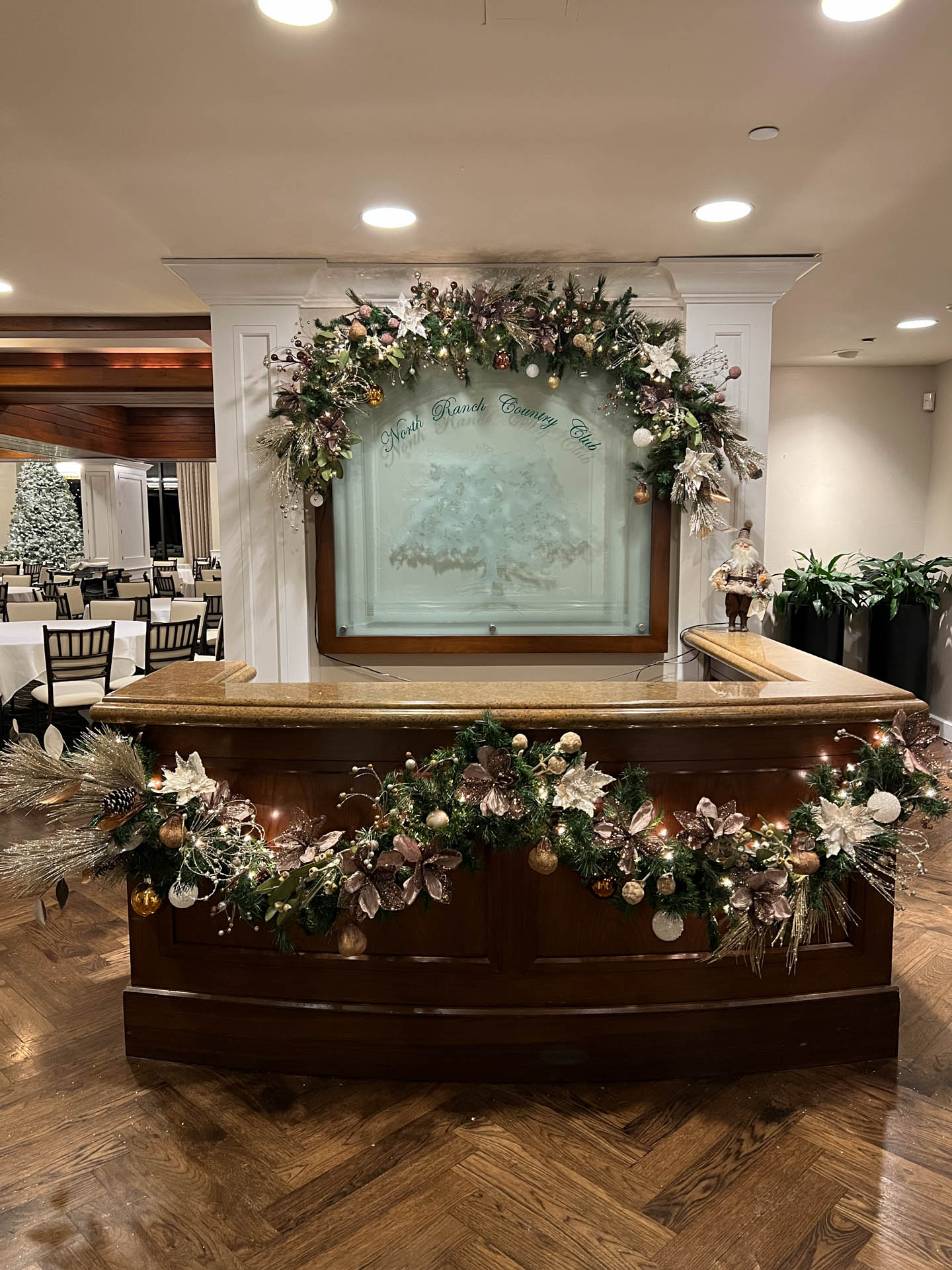 Reception desk area decorated with festive garlands and pine cones at North Ranch Country Club.