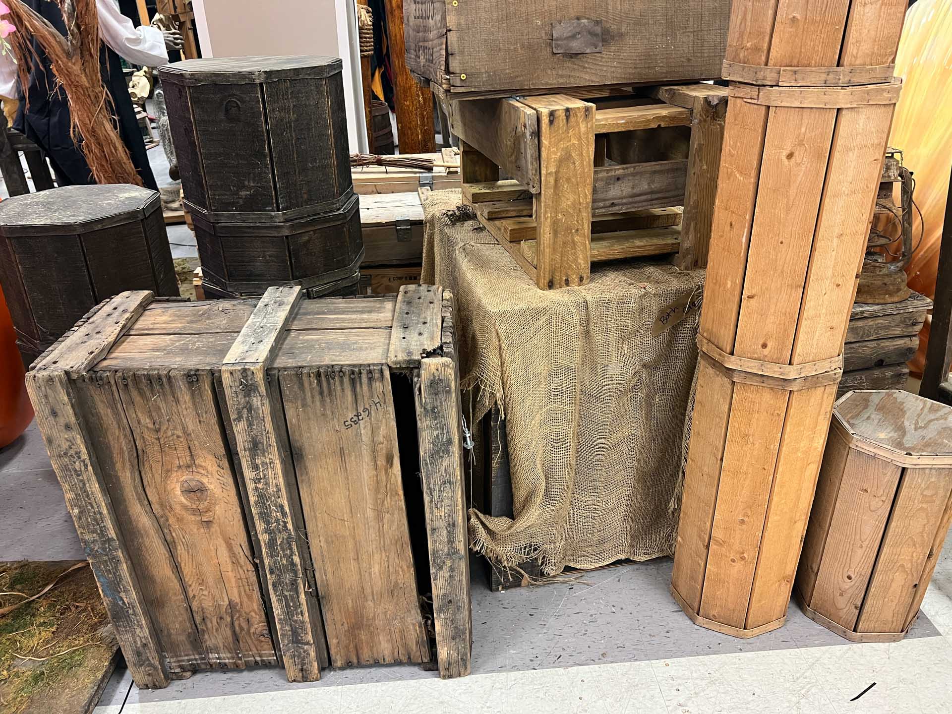 Various old wooden crates and containers stacked on a floor with a burlap cloth-covered crate.