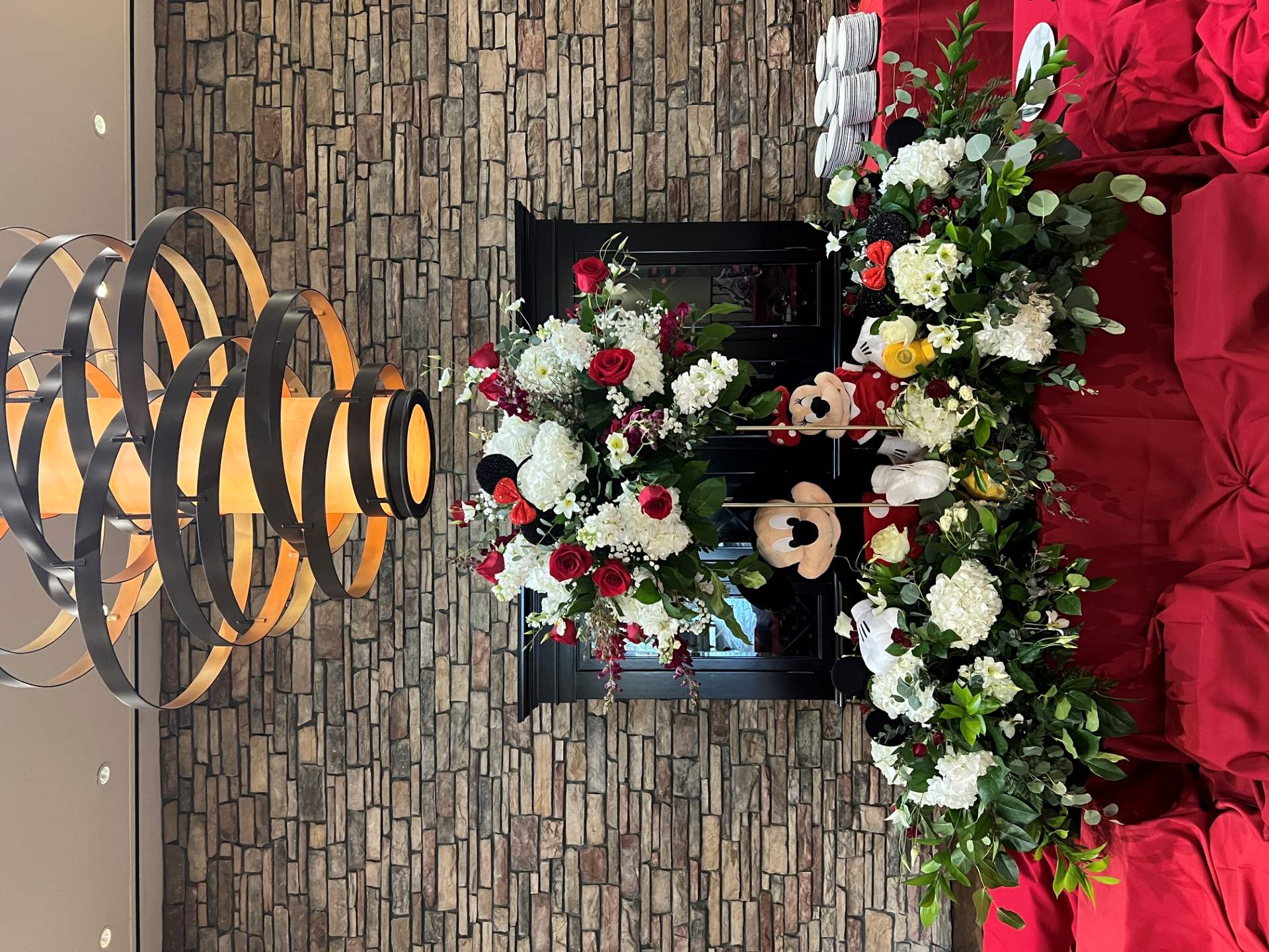 Mickey and Minnie themed floral display with red roses, white hydrangeas, greenery, and character decorations.