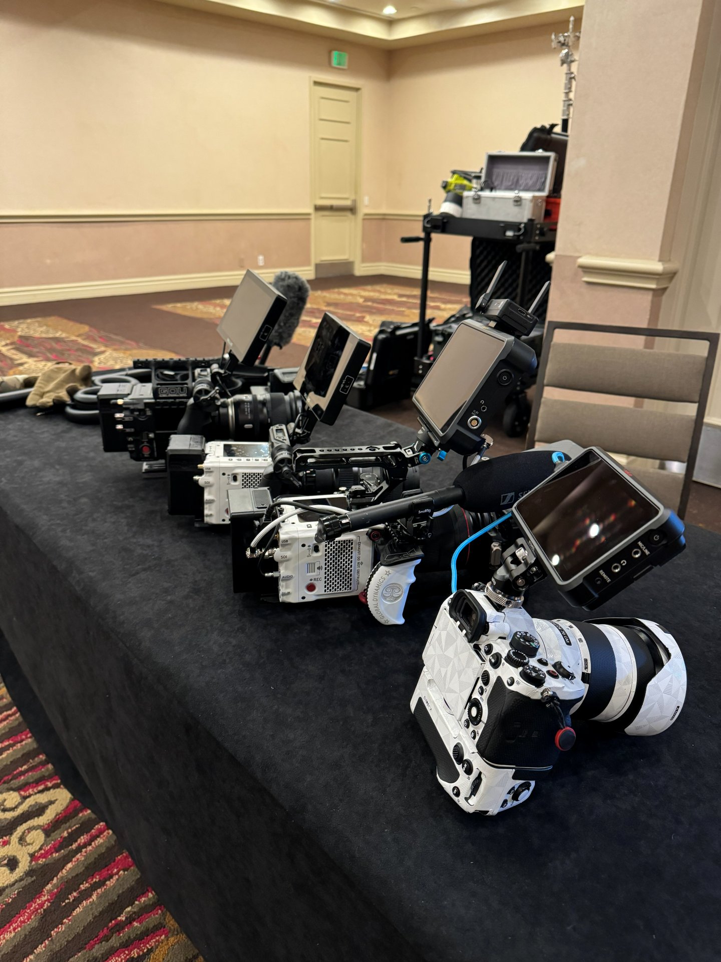 Long black table lined with several high end cinema cameras. 