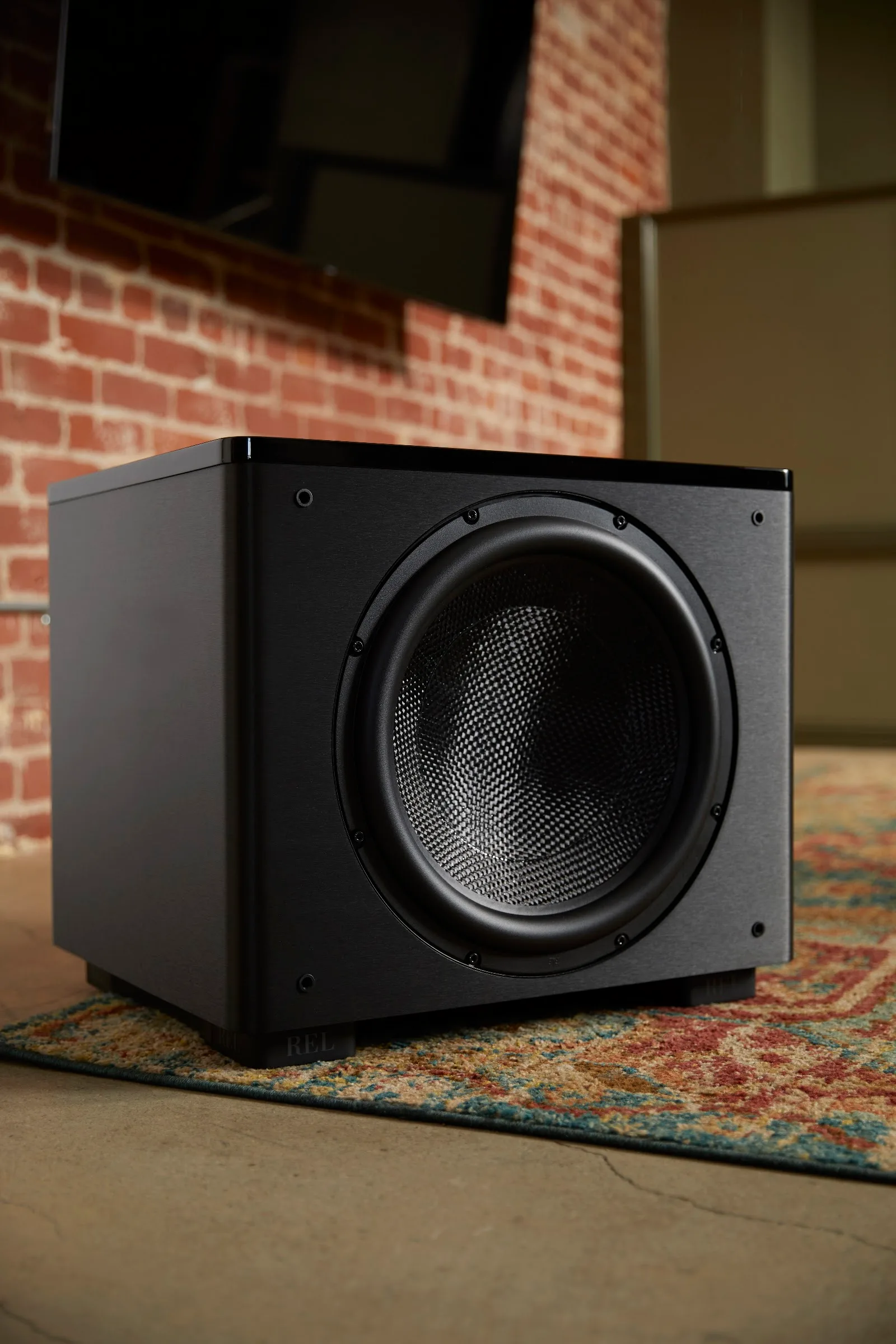REL HT/1510 Predator installed against exposed brick in a dedicated home theatre