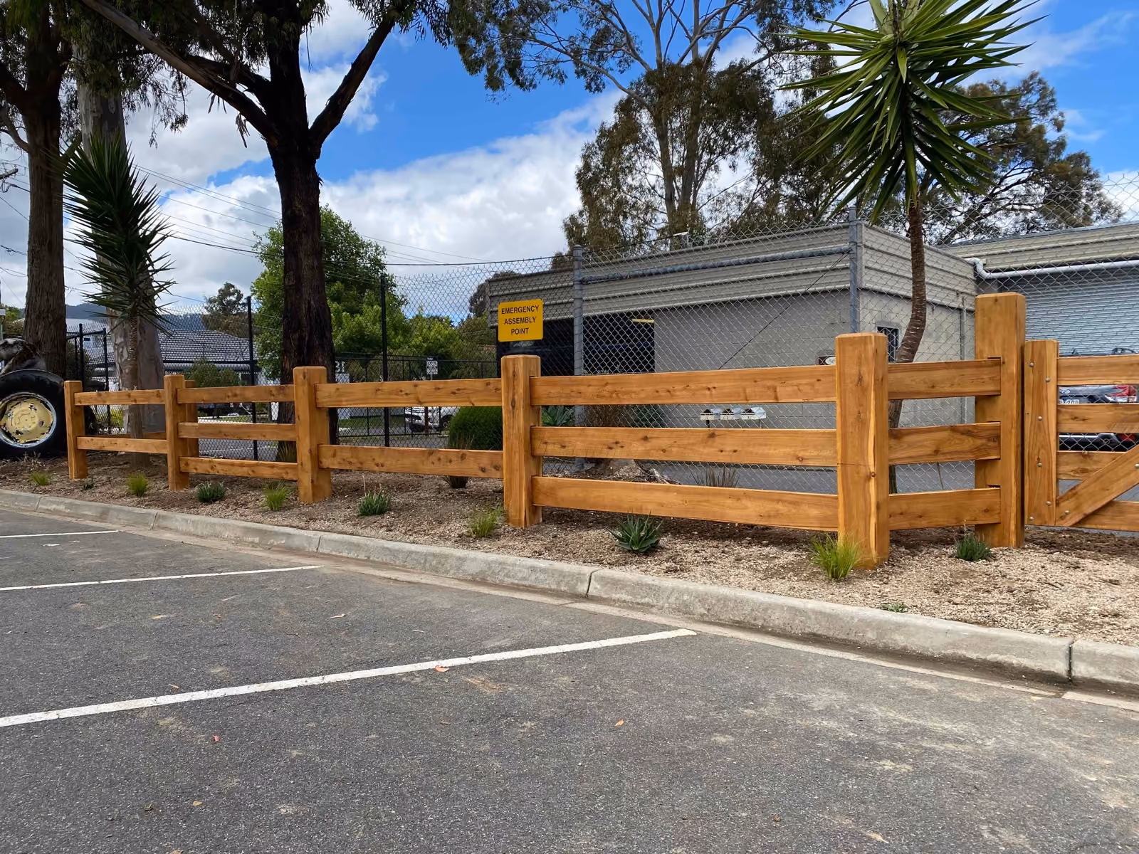 Three-rail cypress post and rail fence along a car park edge