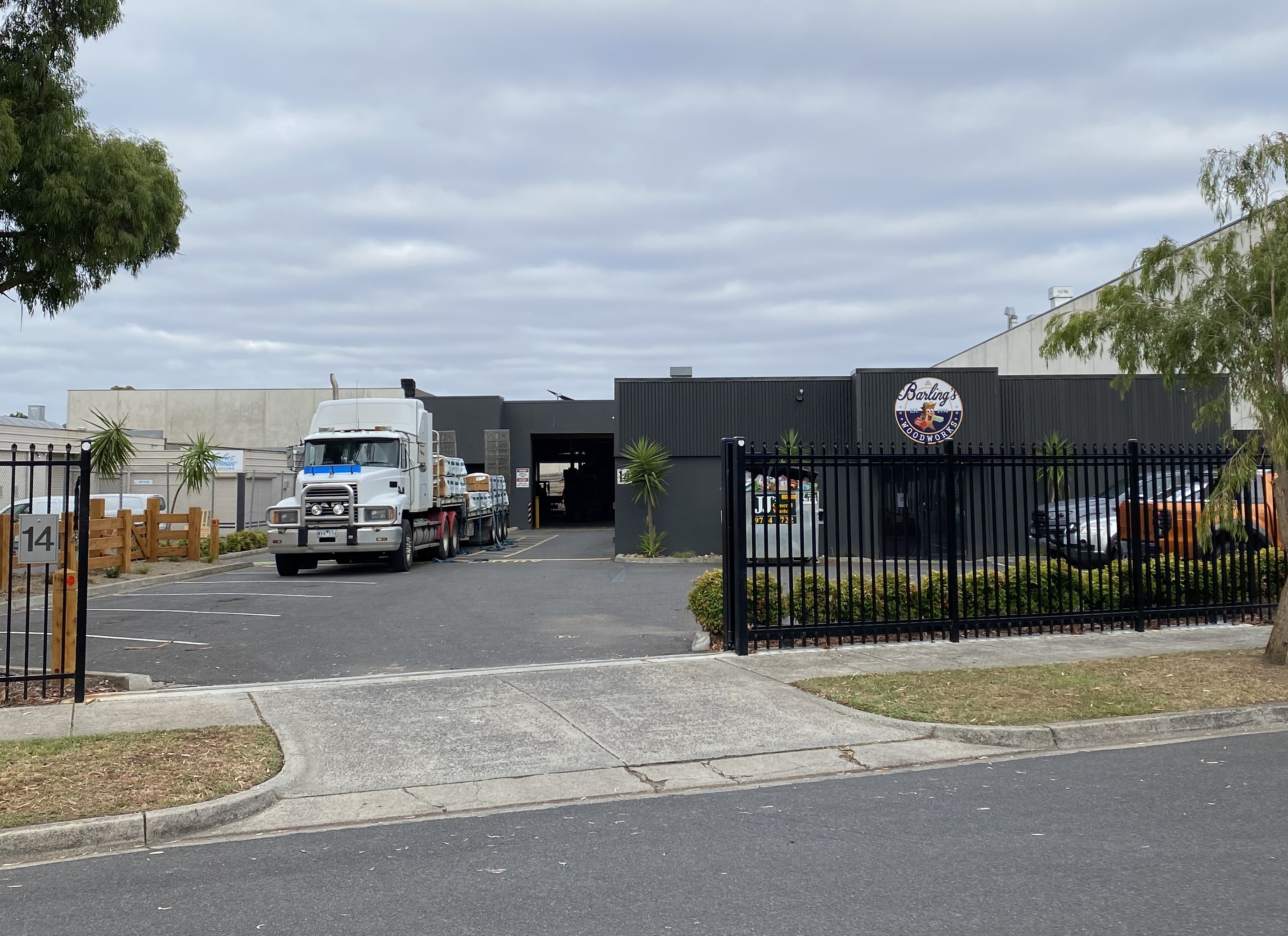 Truck parked outside a black industrial building with a sign reading Barling's Woodworks.