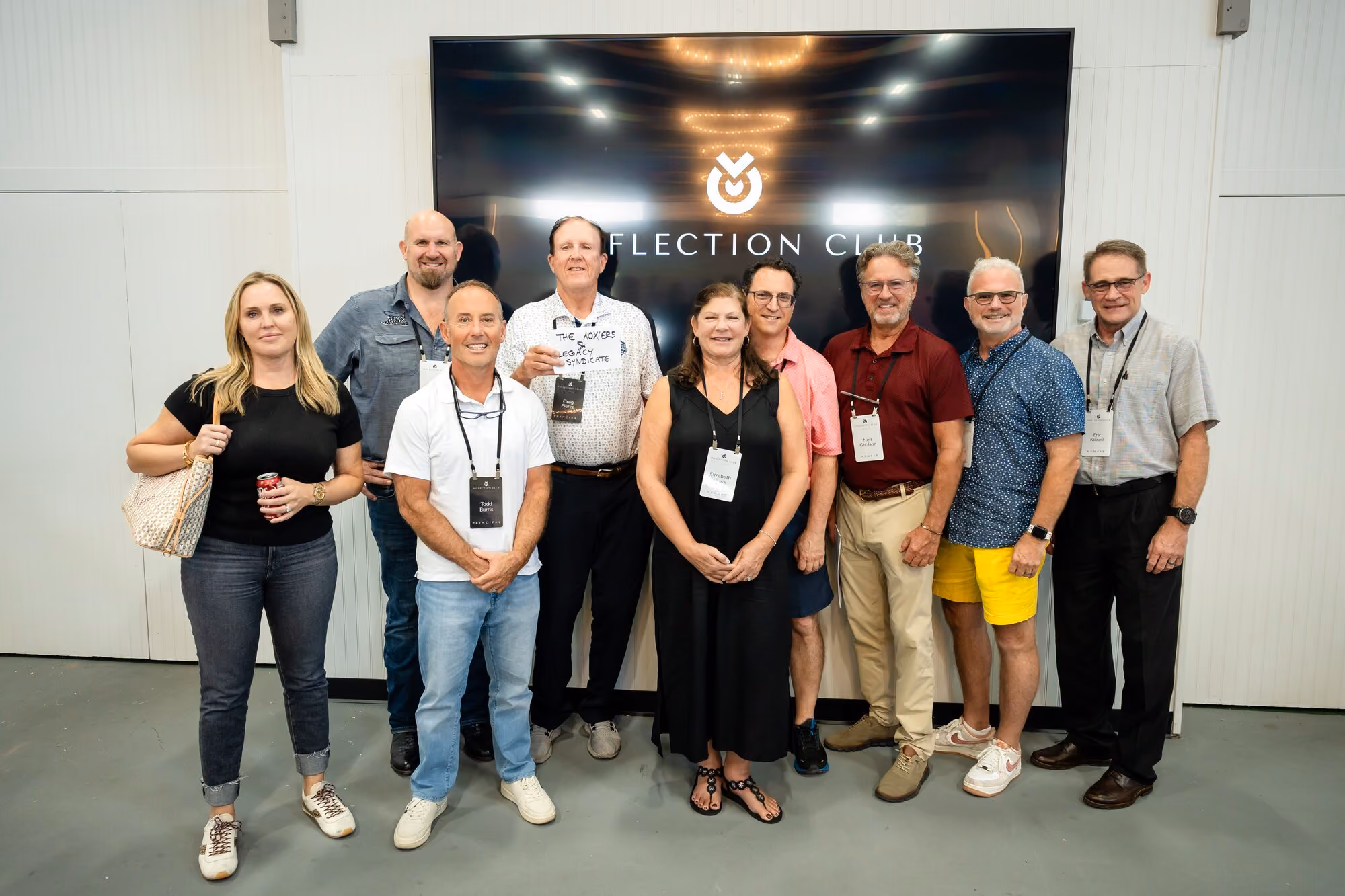 Members grouped in front of the Inflection Club screen