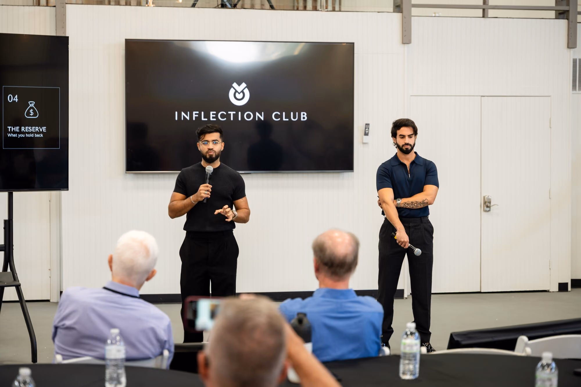 Hosts presenting to members at the front of the room