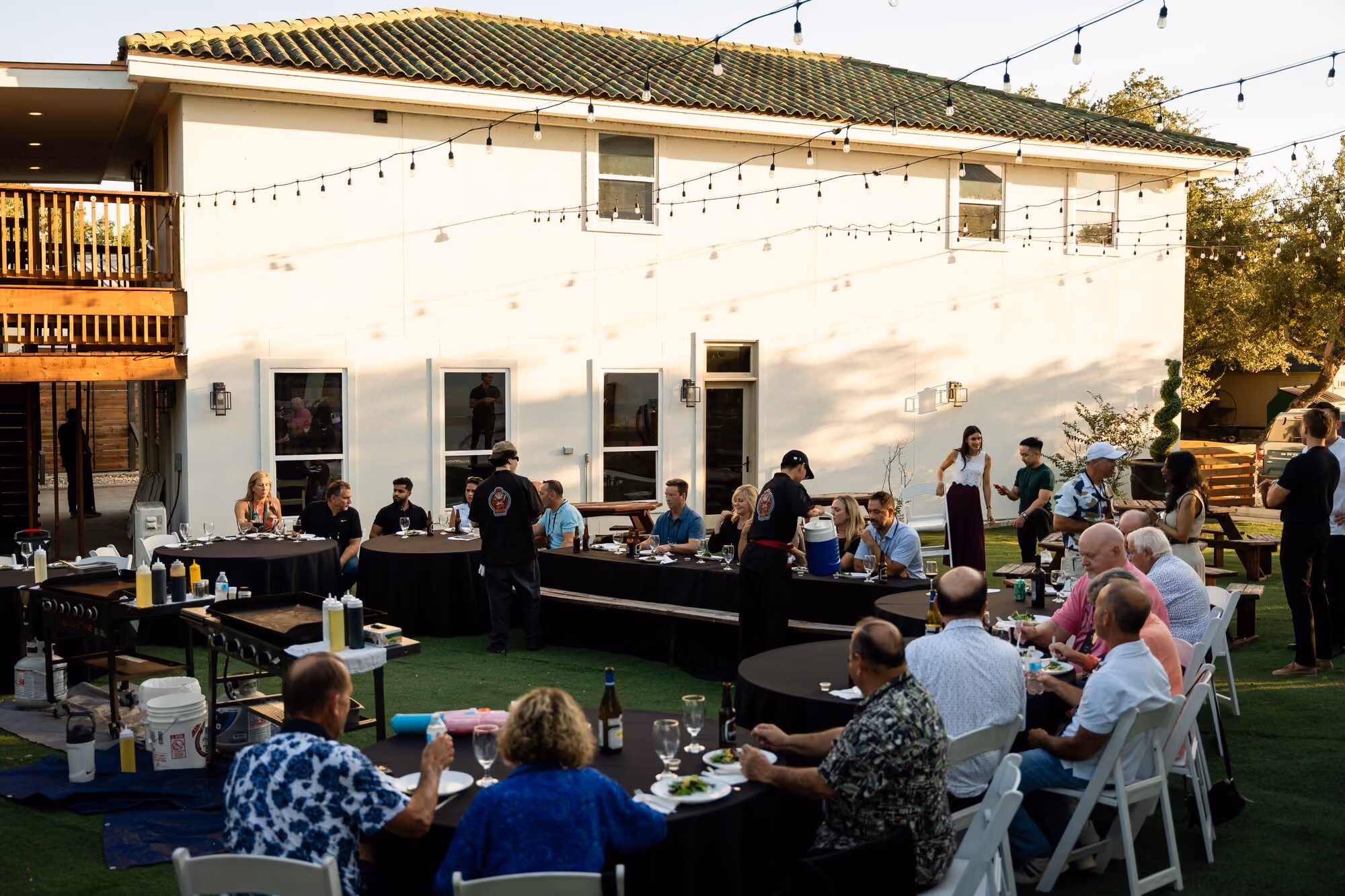 Dinner tables set up outside the venue under string lights