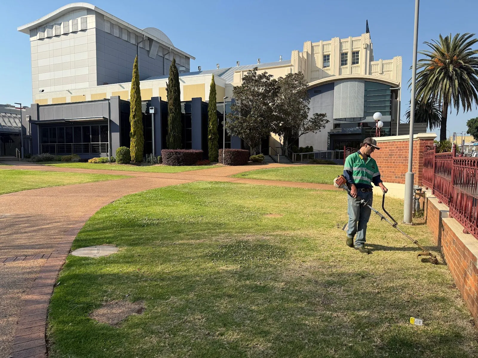 TopLawn crew member whipper-snipping commercial grounds beside a brick path
