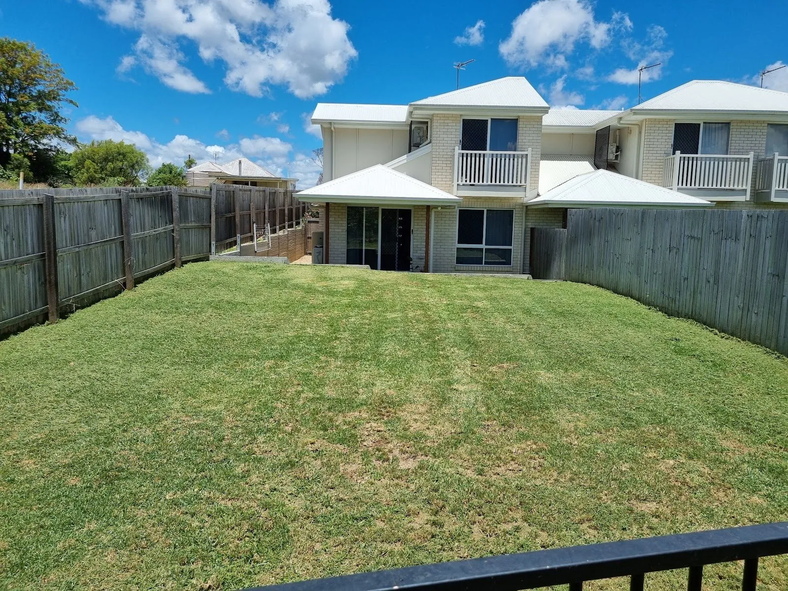Freshly mowed backyard lawn behind a two-storey unit