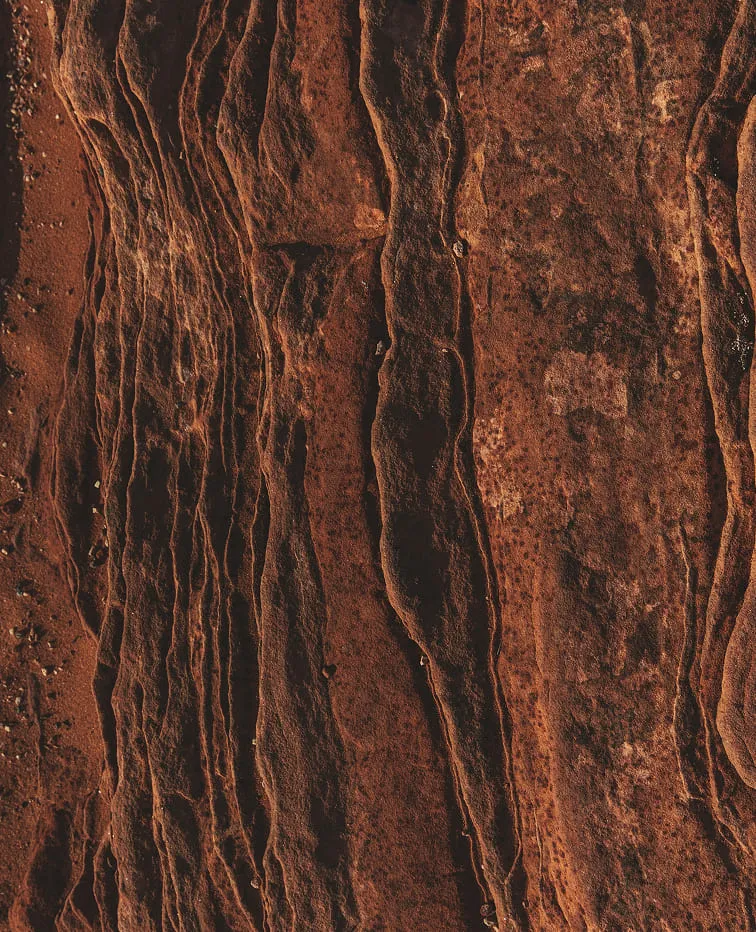 Close-up of textured, weathered brown rock formations with deep crevices and rough surfaces.