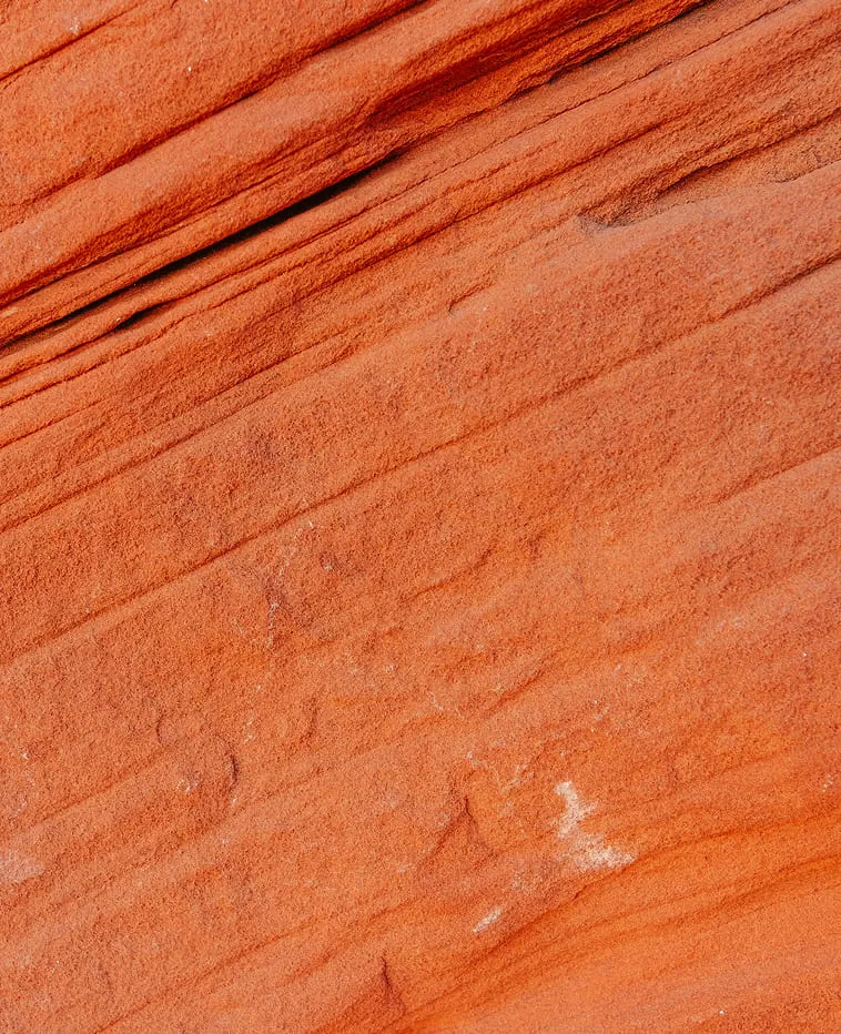 Close-up of orange layered sandstone showing natural erosion textures and lines.