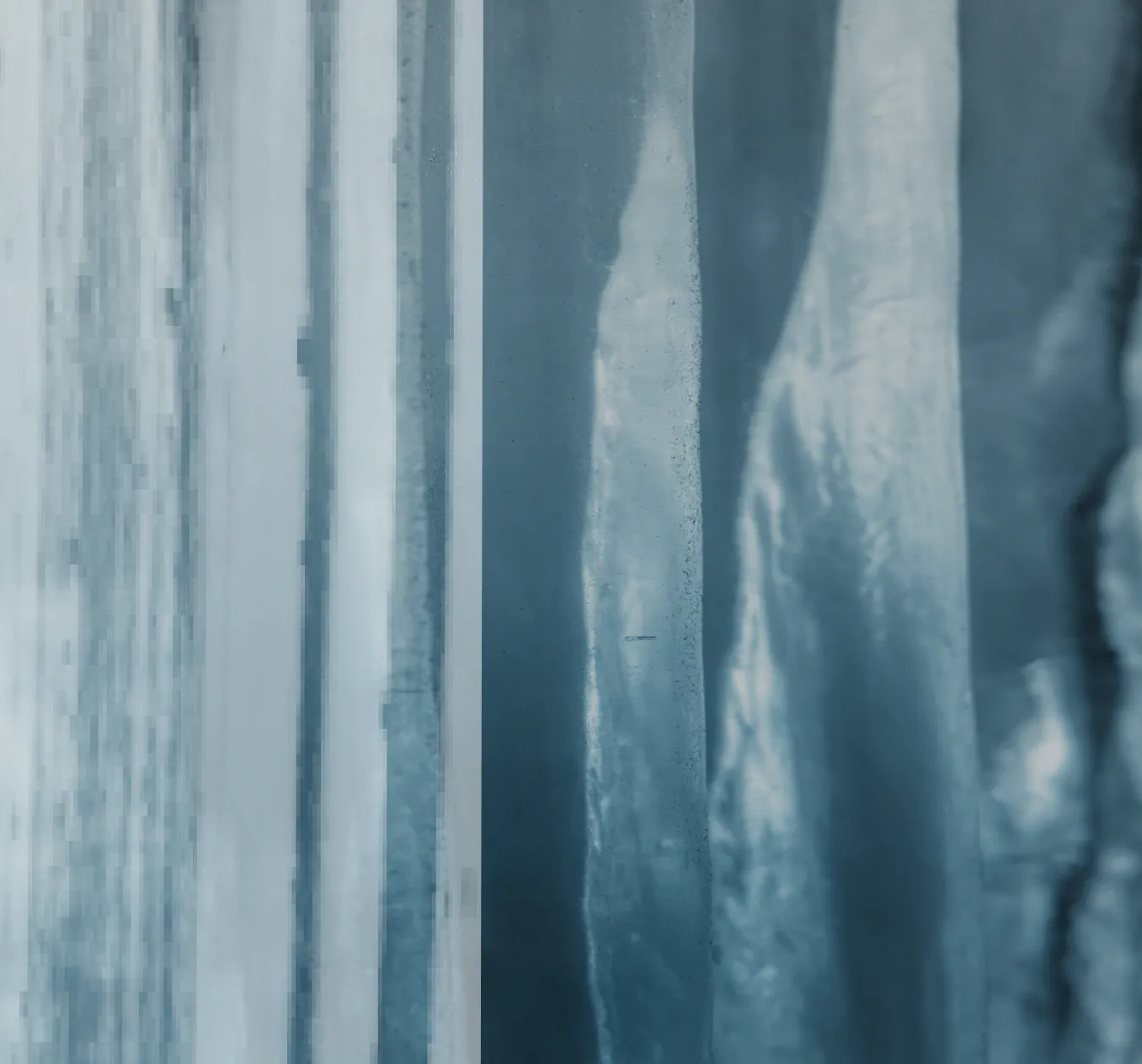 Close-up view of vertical translucent blue ice columns with textured surfaces.