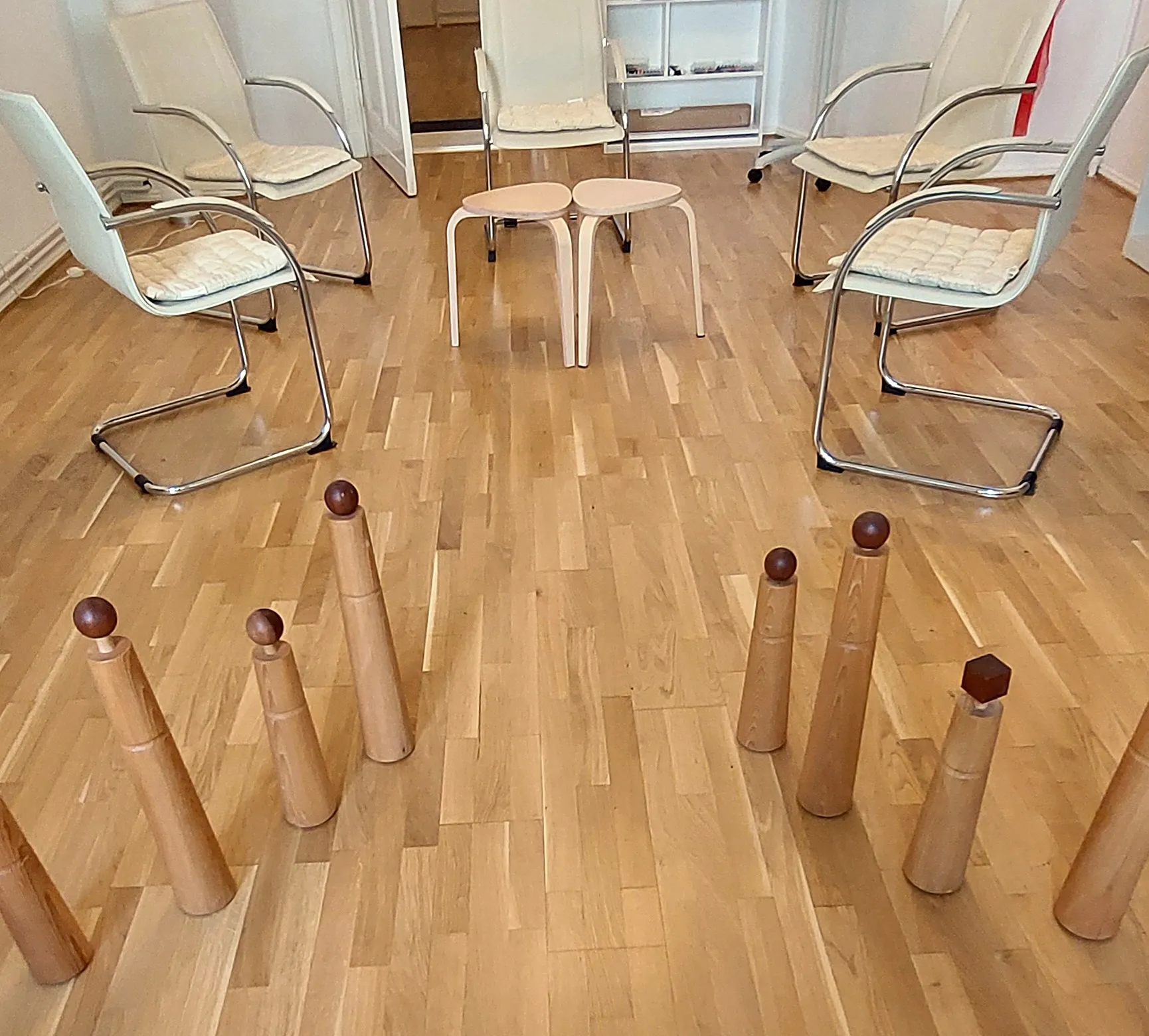 Holzfiguren auf dem Parkettboden vor einem Stuhlkreis im Praxisraum