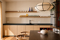 Cozy modern dining room with a wooden table, bench seating, pendant light, and shelves with decor.
