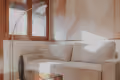 Cozy beige sectional sofa with cushions next to a wooden coffee table near windows.