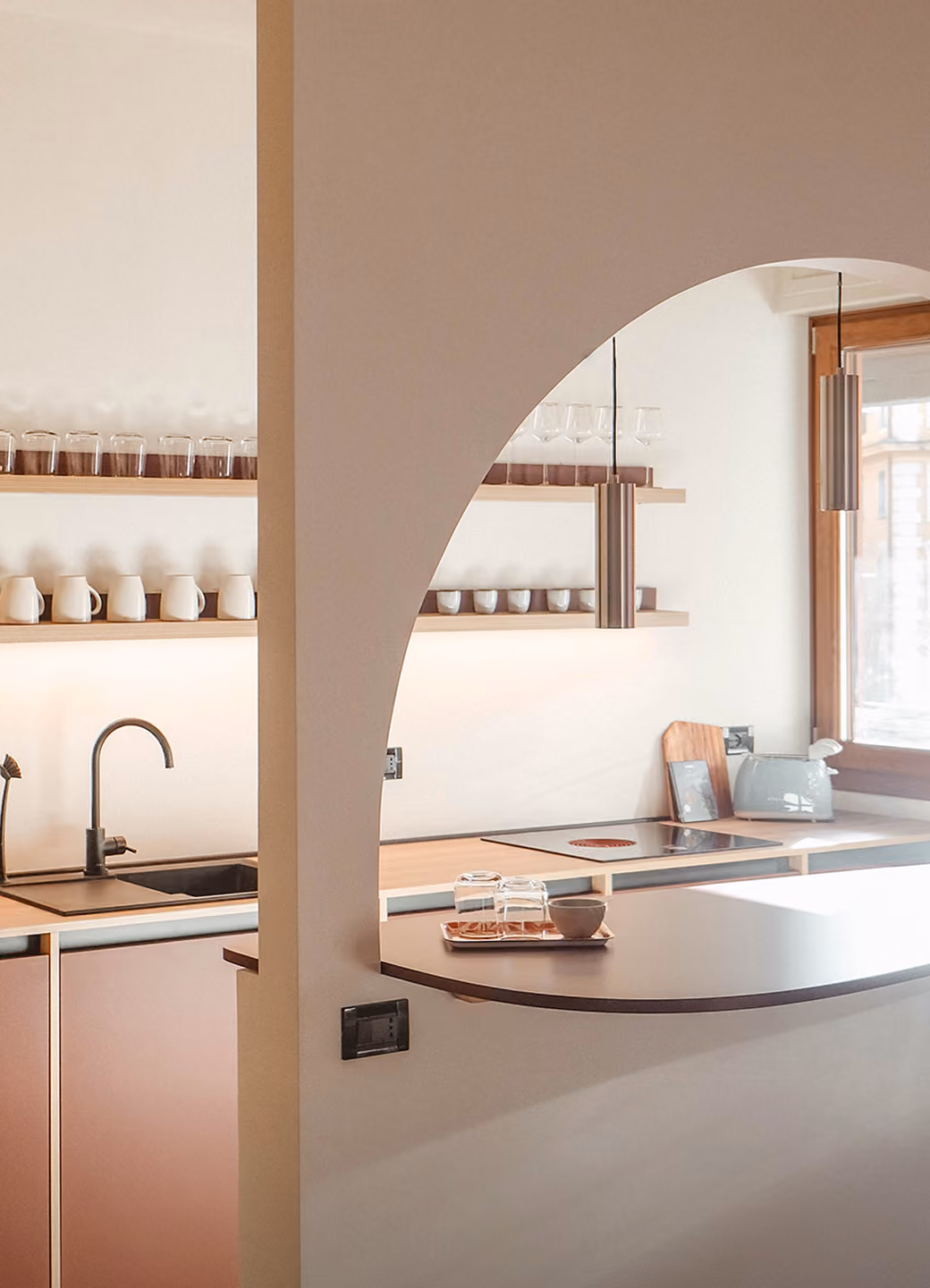 Modern kitchen with open shelves, black faucet, cooktop, and countertop with glasses and bowl.