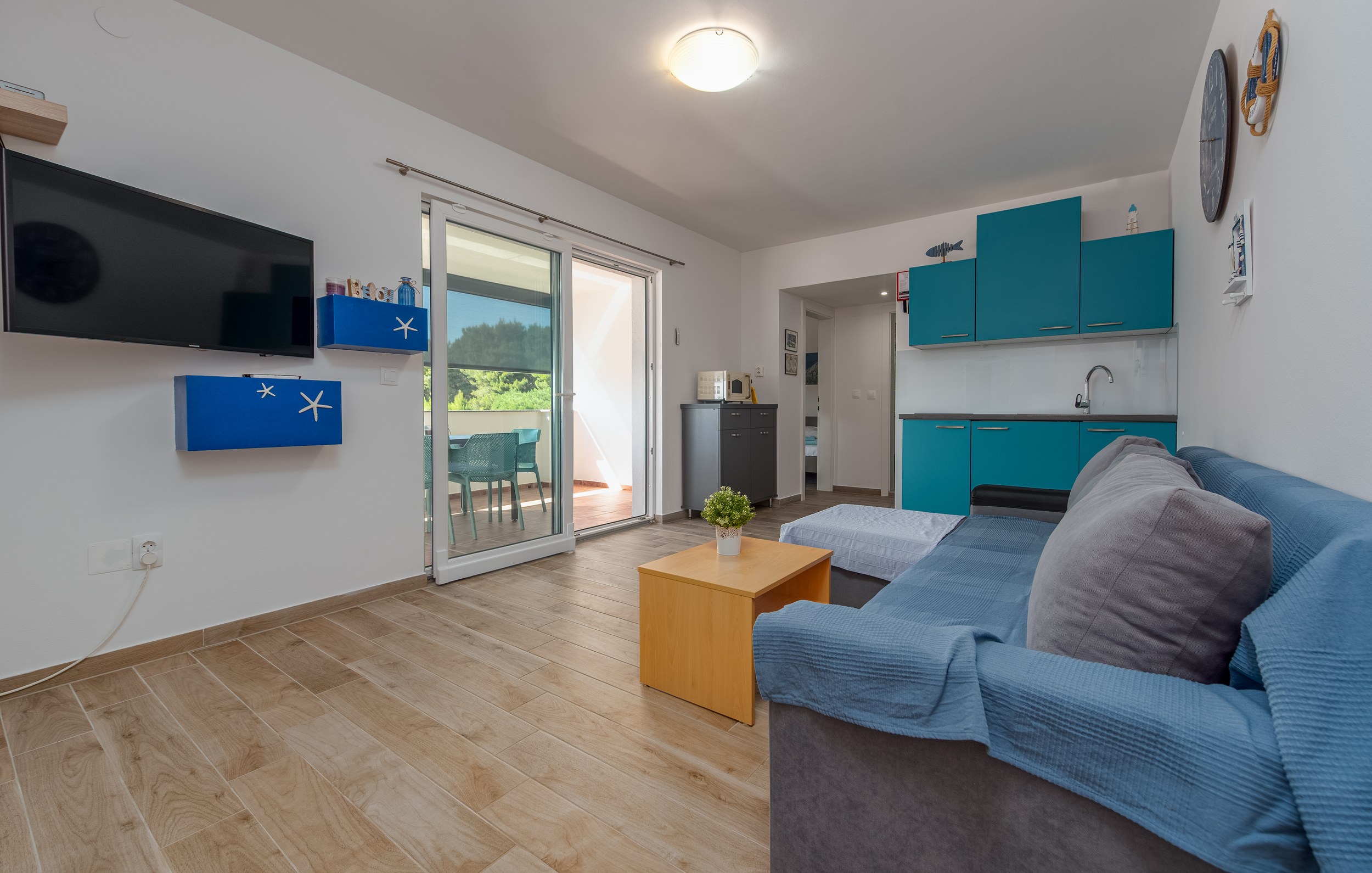 Living room with turquoise kitchen and terrace doors, Apartment Blue