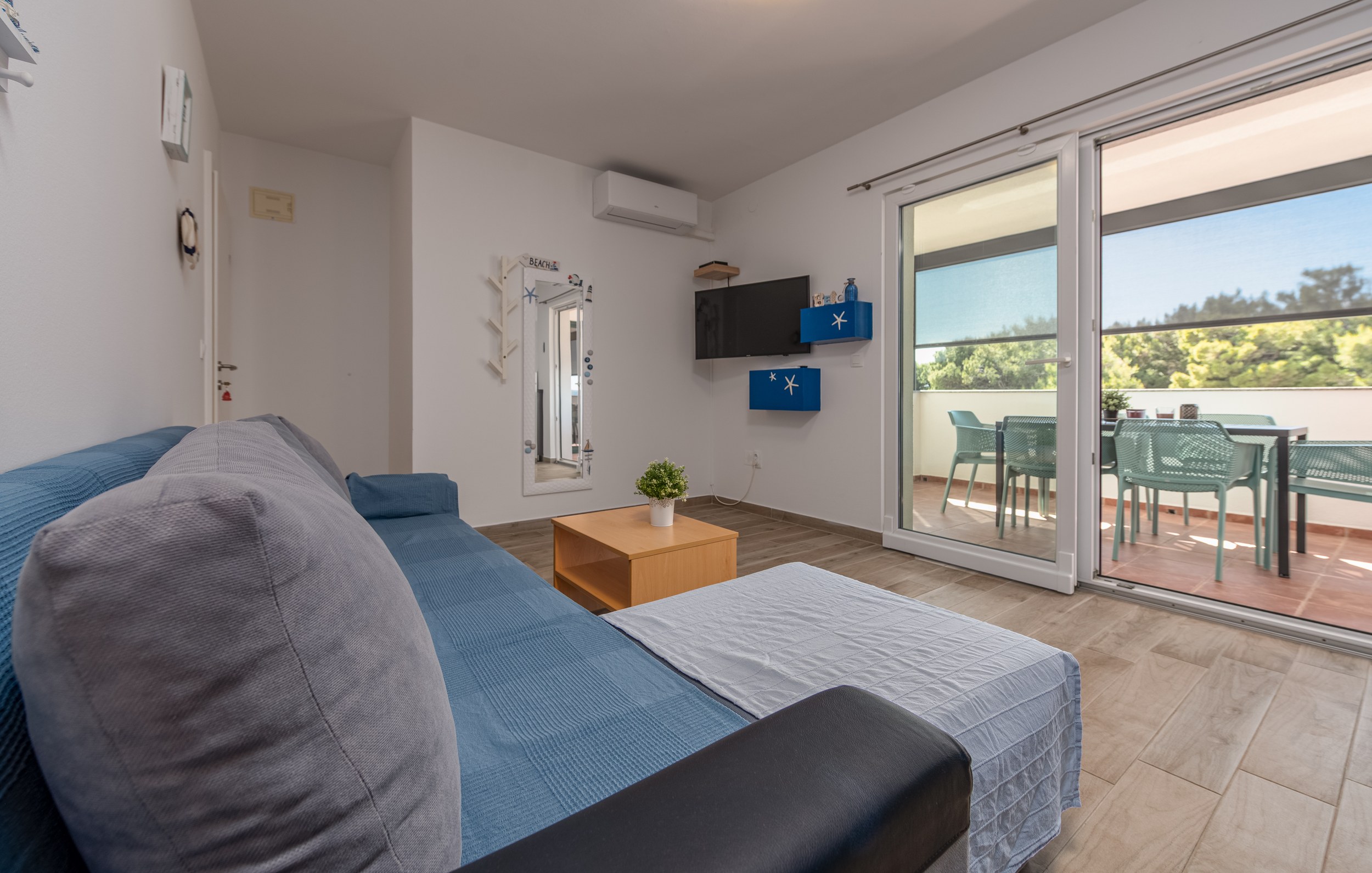 Sofa bed and terrace doors with sea beyond, Apartment Blue
