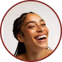 Smiling woman with braided hair looking upwards against a white background.