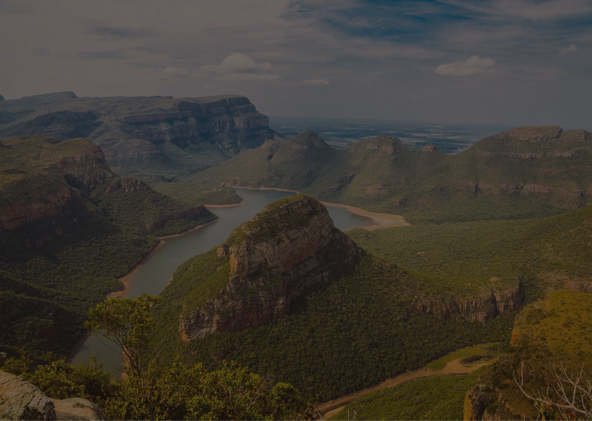 River winding through green forested mountains under a partly cloudy sky.