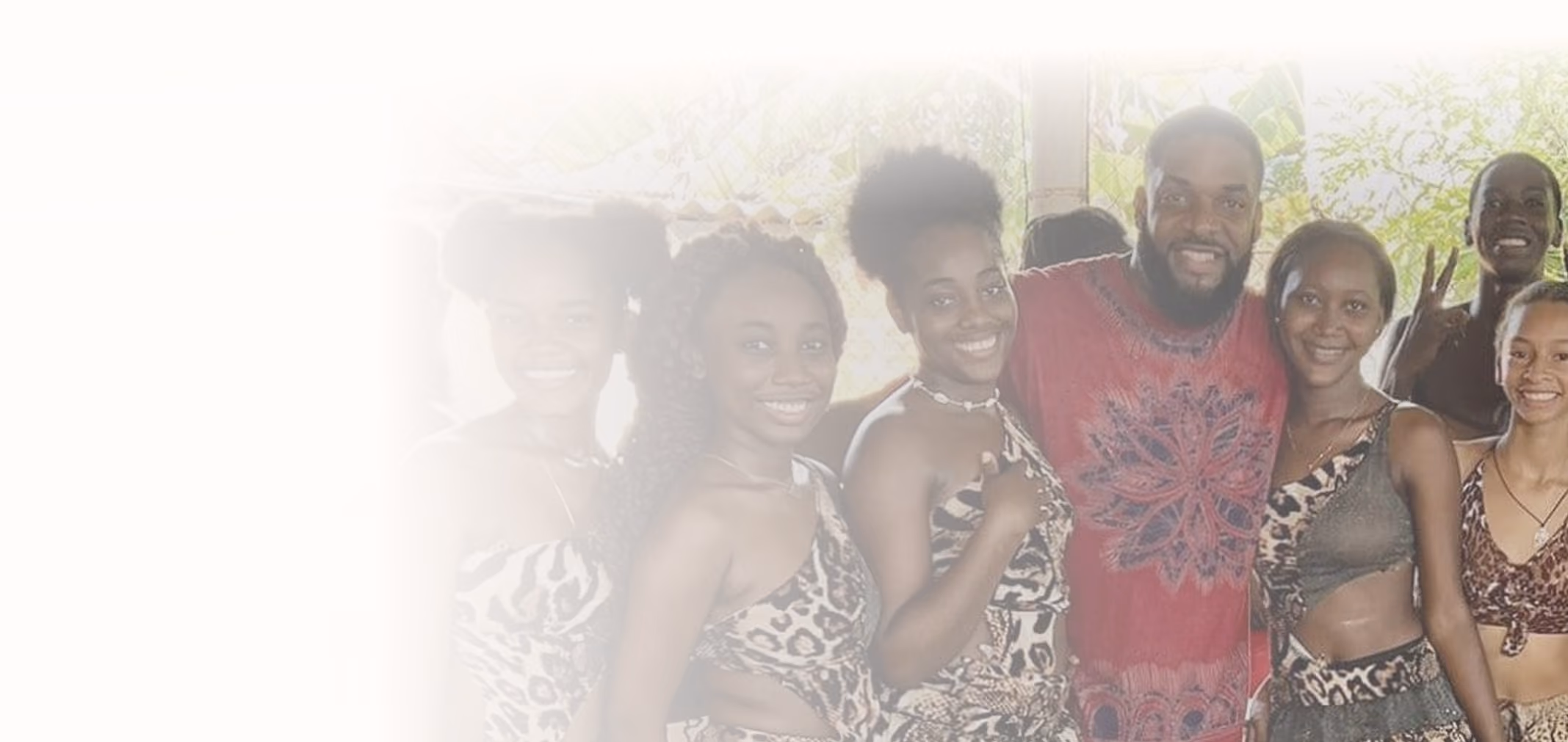 Group of smiling people in animal print clothing posing together near a window with greenery outside.