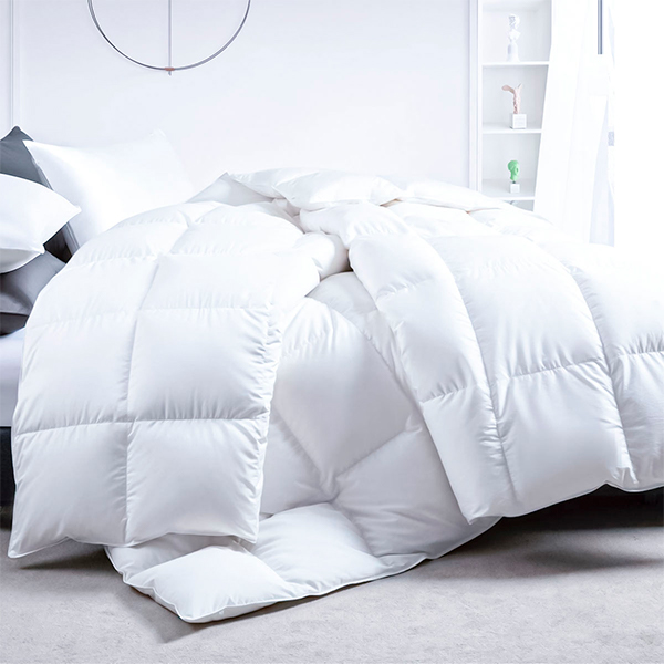 Edredón blanco mullido colocado sobre cama en una habitación iluminada y moderna.