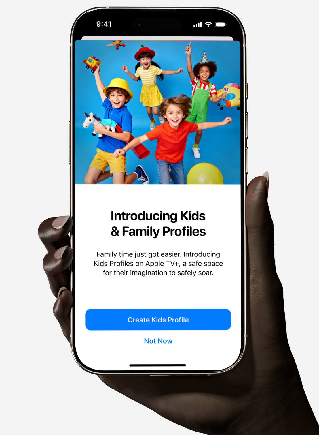 Hand holding phone showing Apple TV+ Kids & Family Profiles feature with kids playing and a create profile button.
