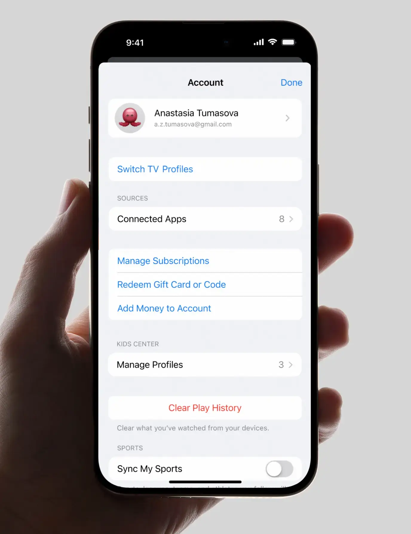 Hand holding phone showing account settings with profile, app connections, subscriptions, and play history options.