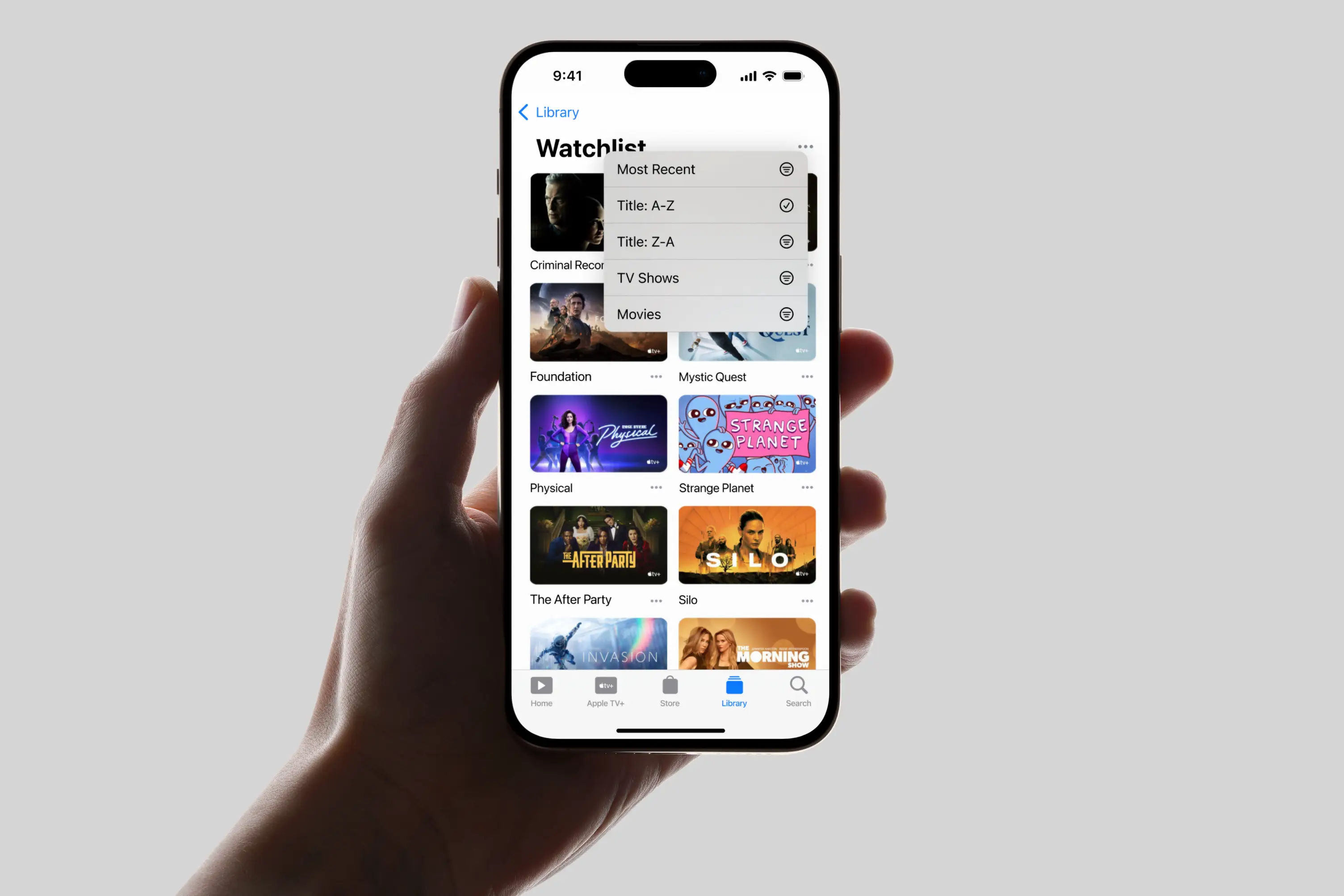 Hand holding iPhone showing Apple TV Watchlist with various TV shows and sorting options menu.