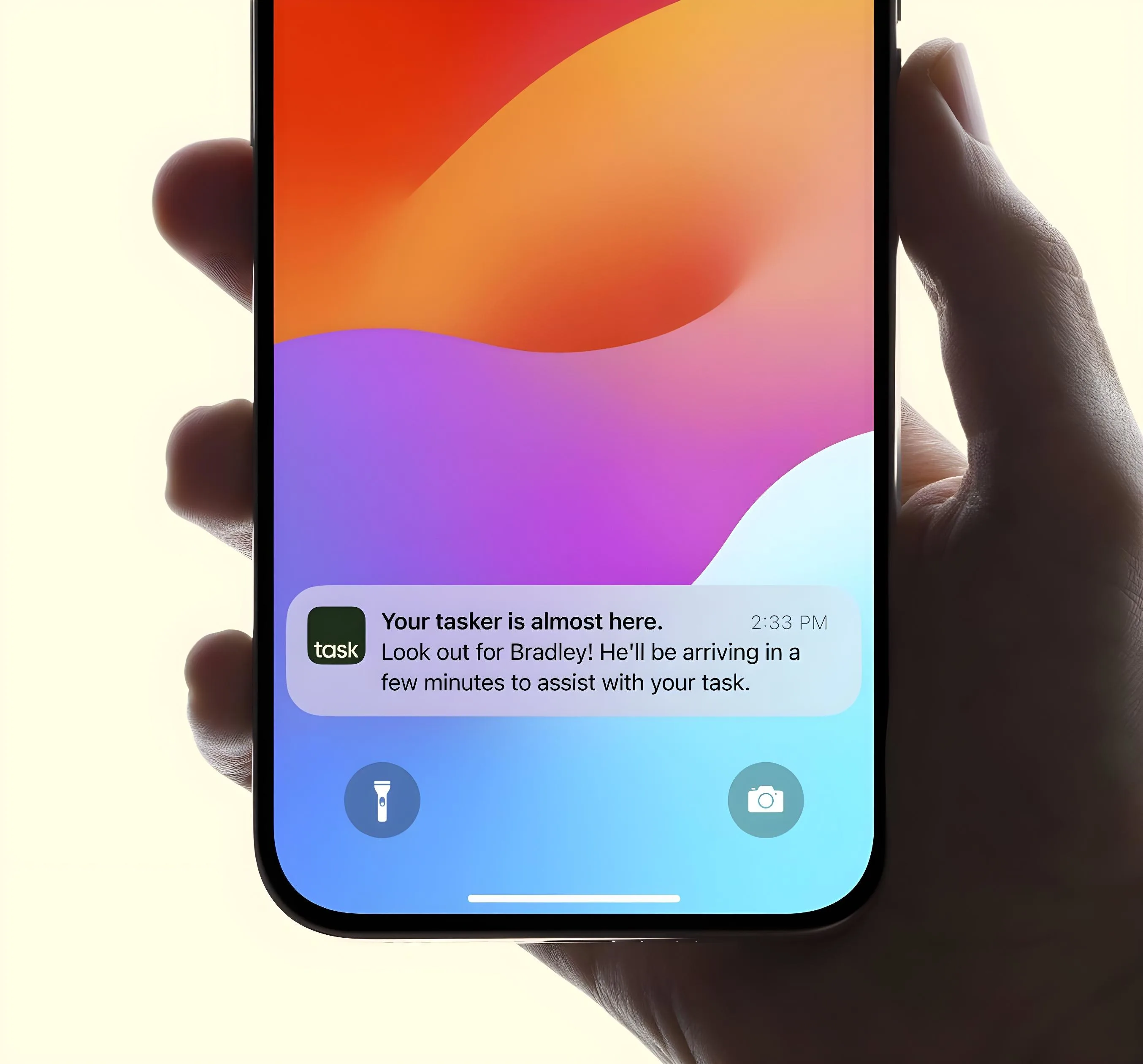 Smartphone showing a push notification about tasker Bradley arriving soon to assist with a task.