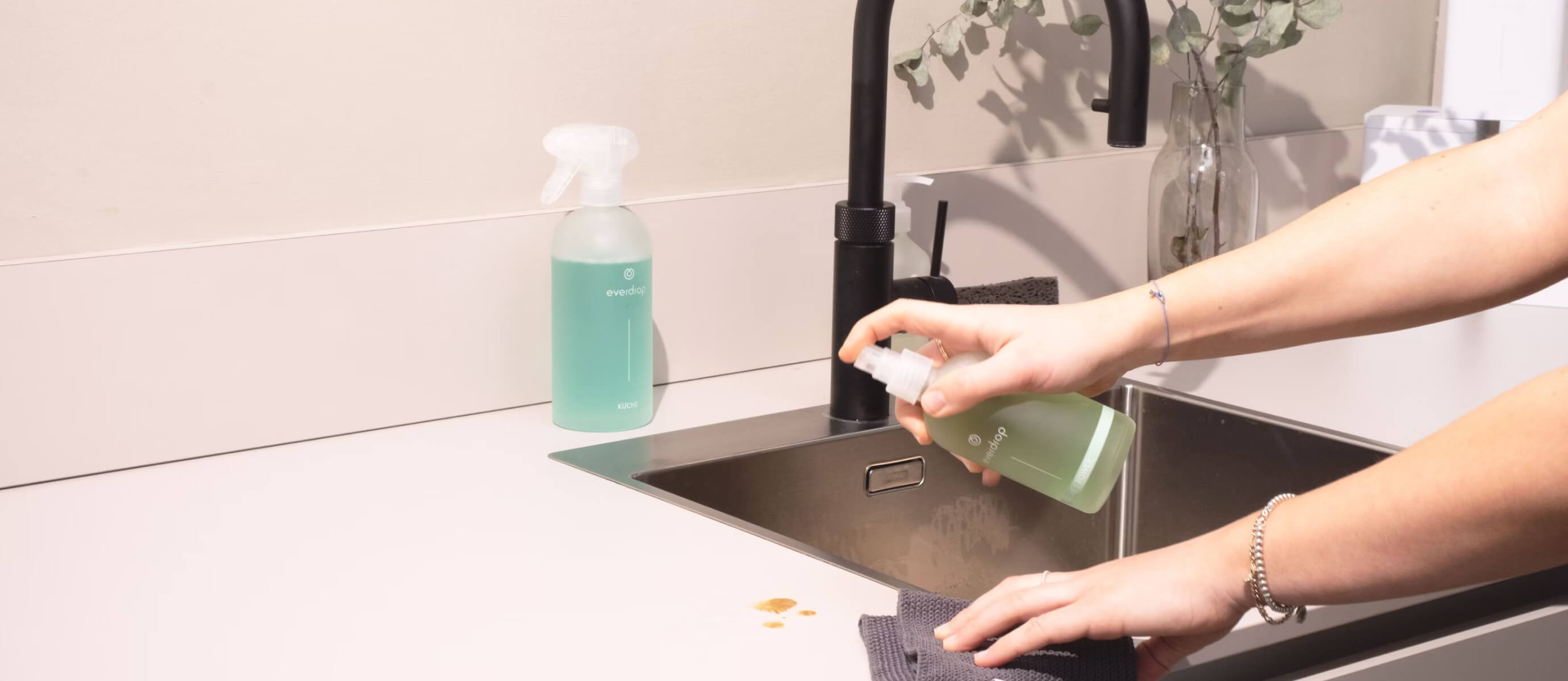 a woman is cleaning a kitchen sink with a rag