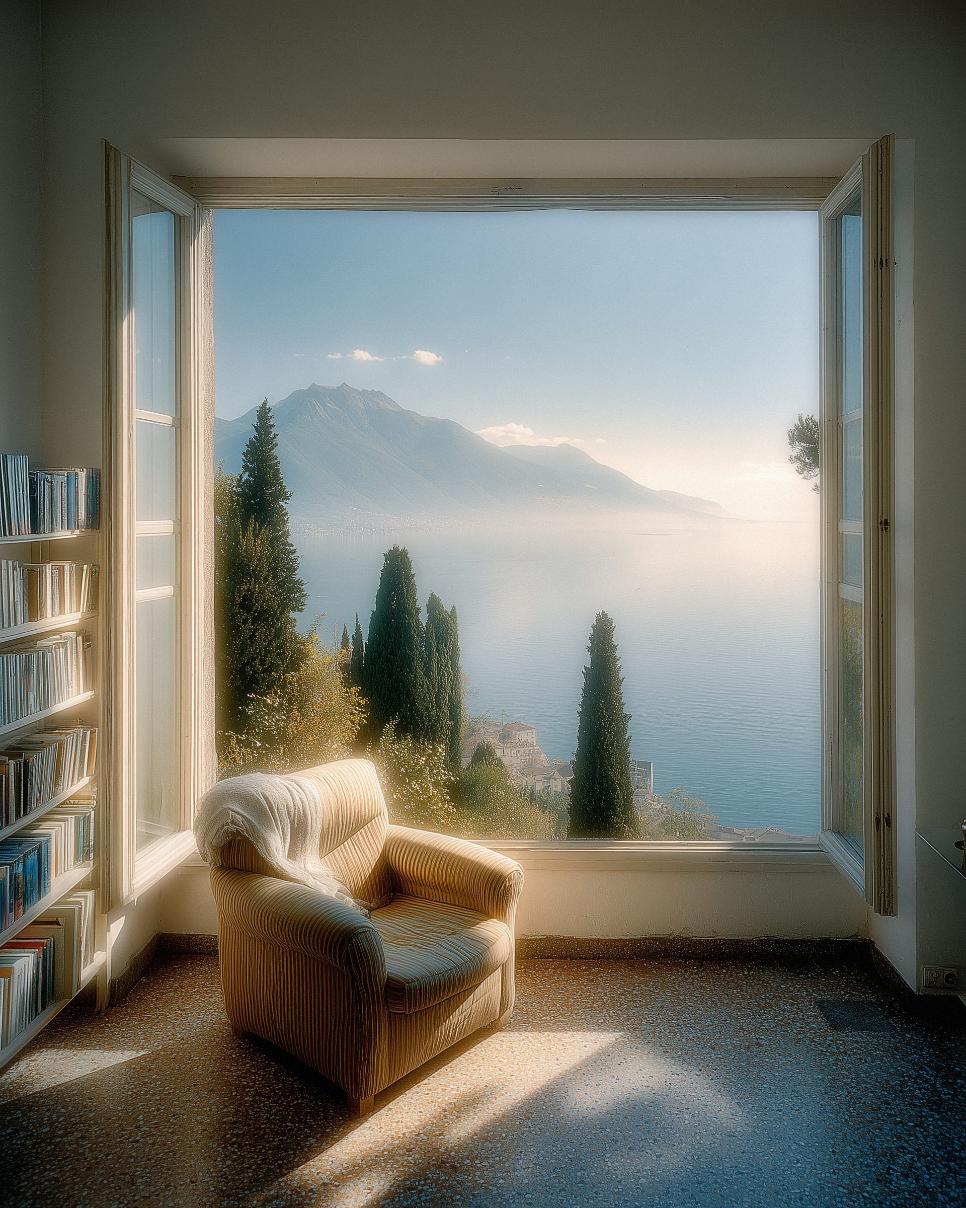 An armchair by an open window over the lake, a wall of books