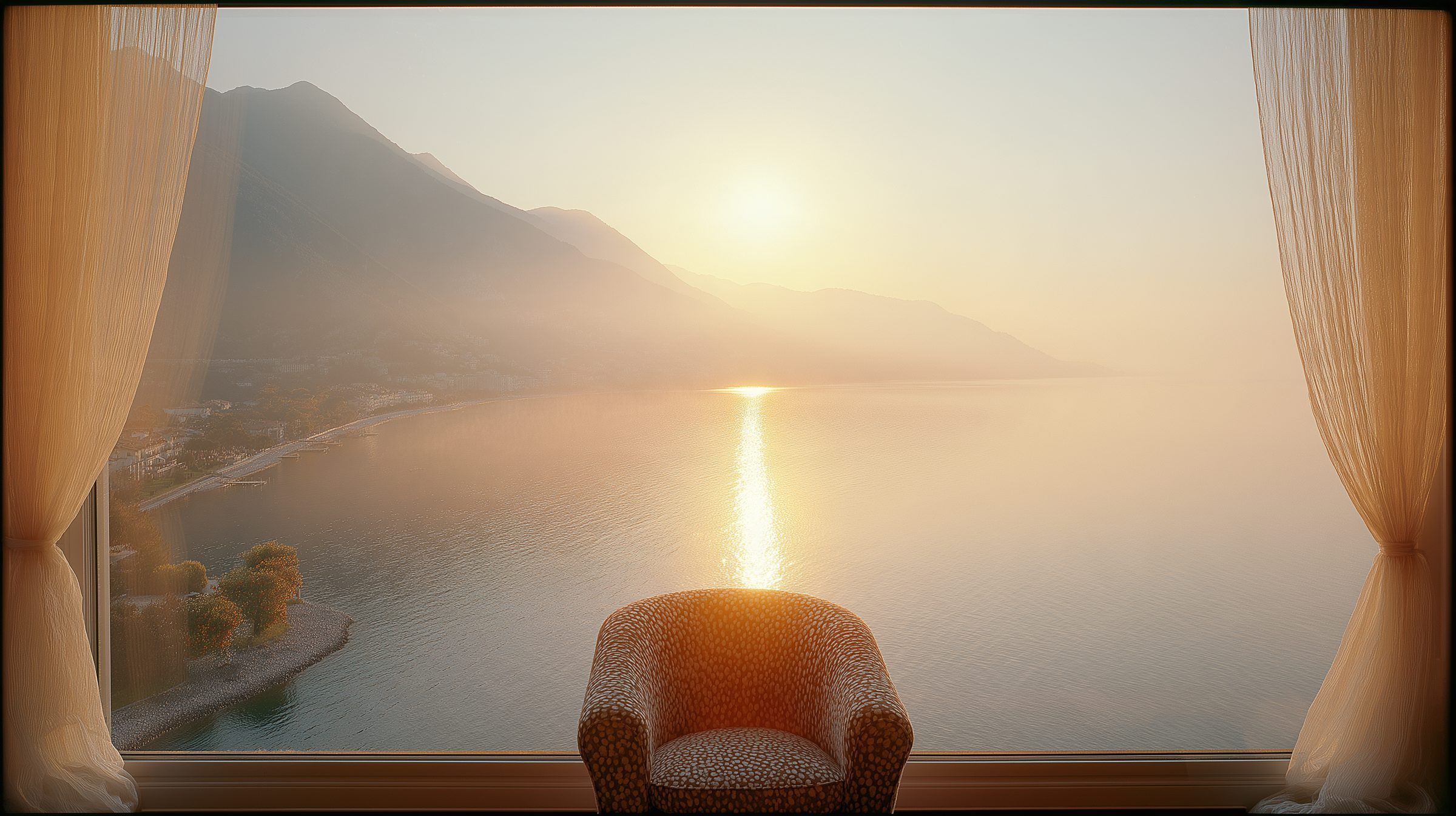 An armchair before a window, the sun rising over the lake