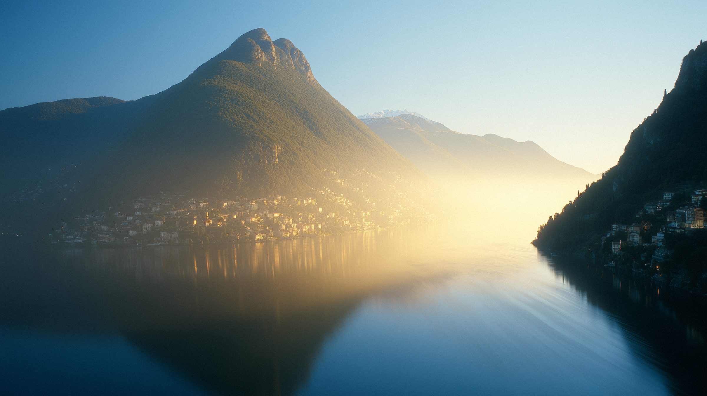 Still water reflecting the mountains in the morning sun