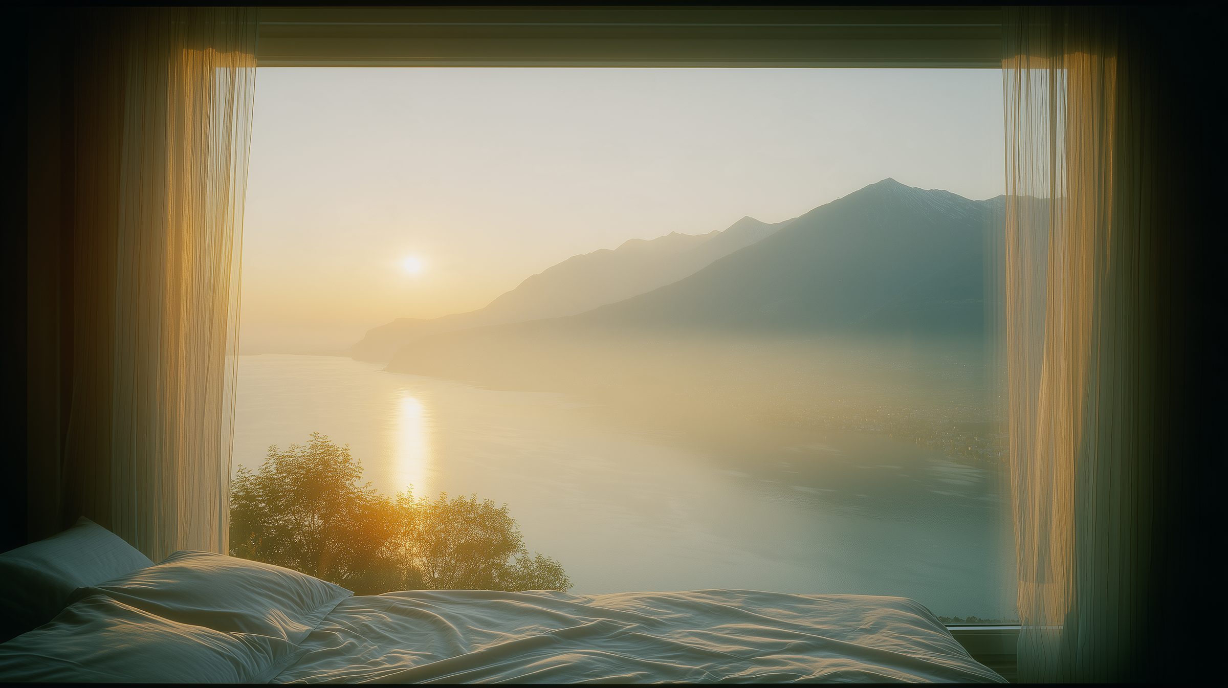A bed by an open window on the lake at sunrise