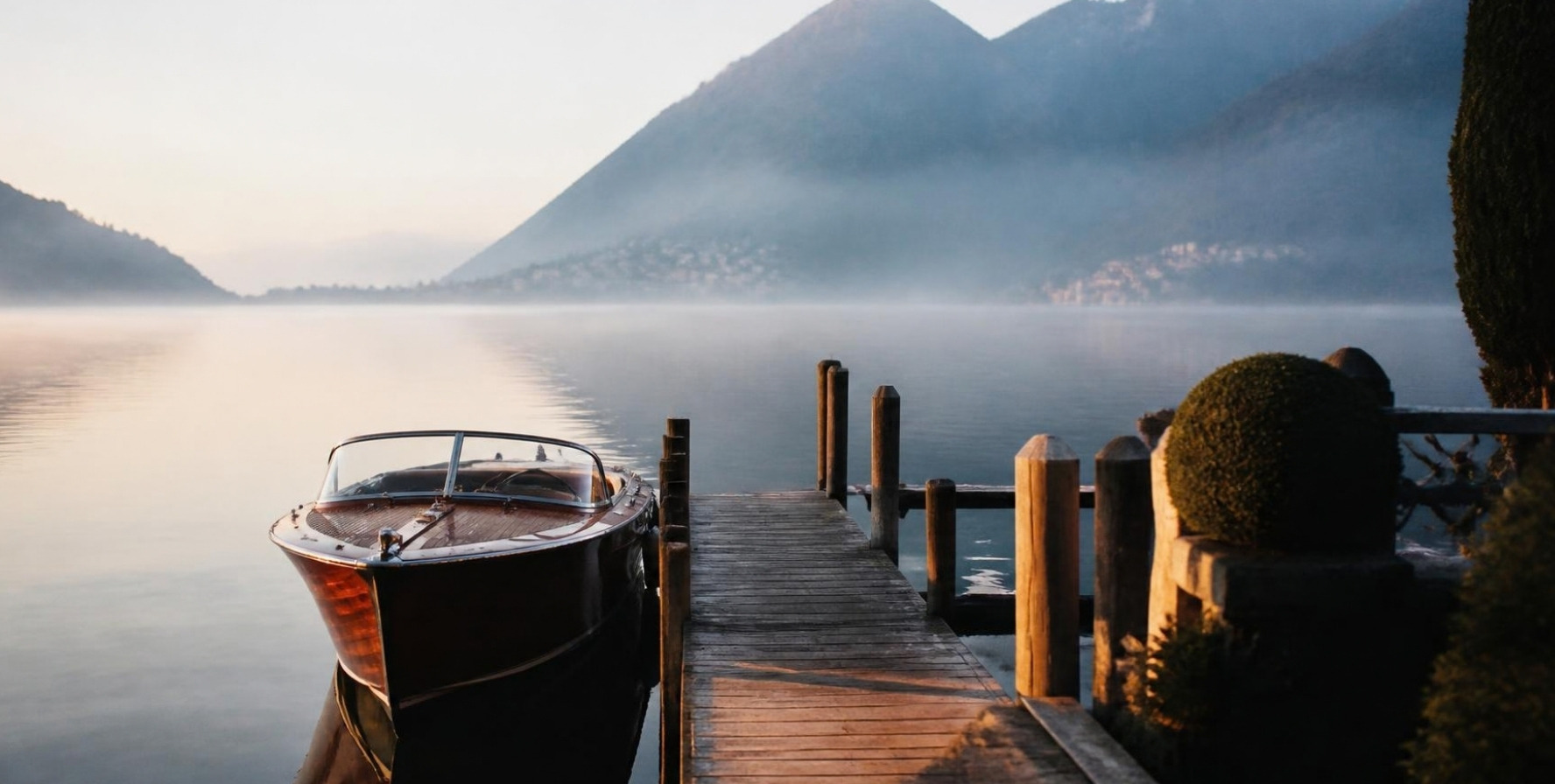 A private wooden jetty and a moored motorboat on the still lake at dawn