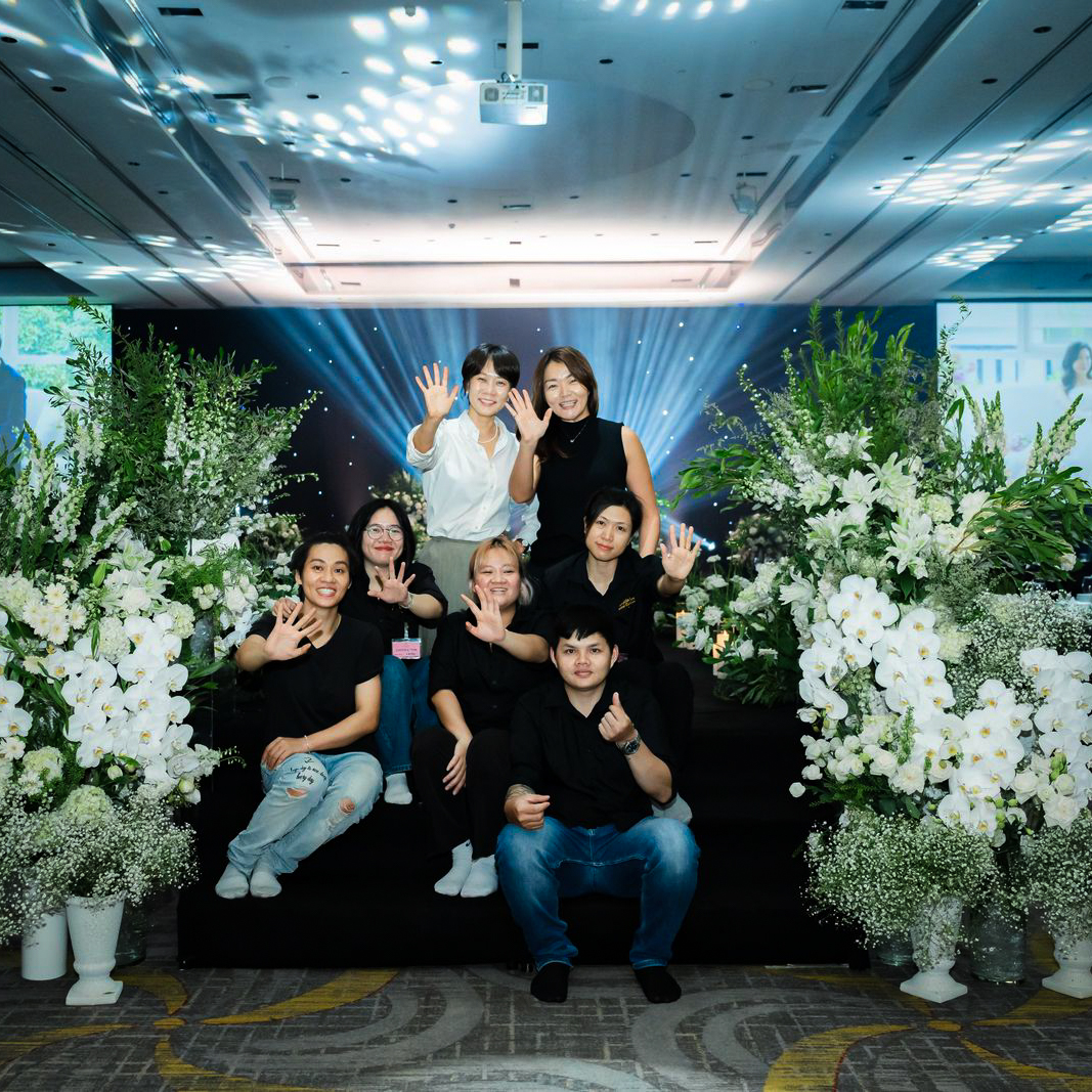 Team group photo posing beside white floral installations at event