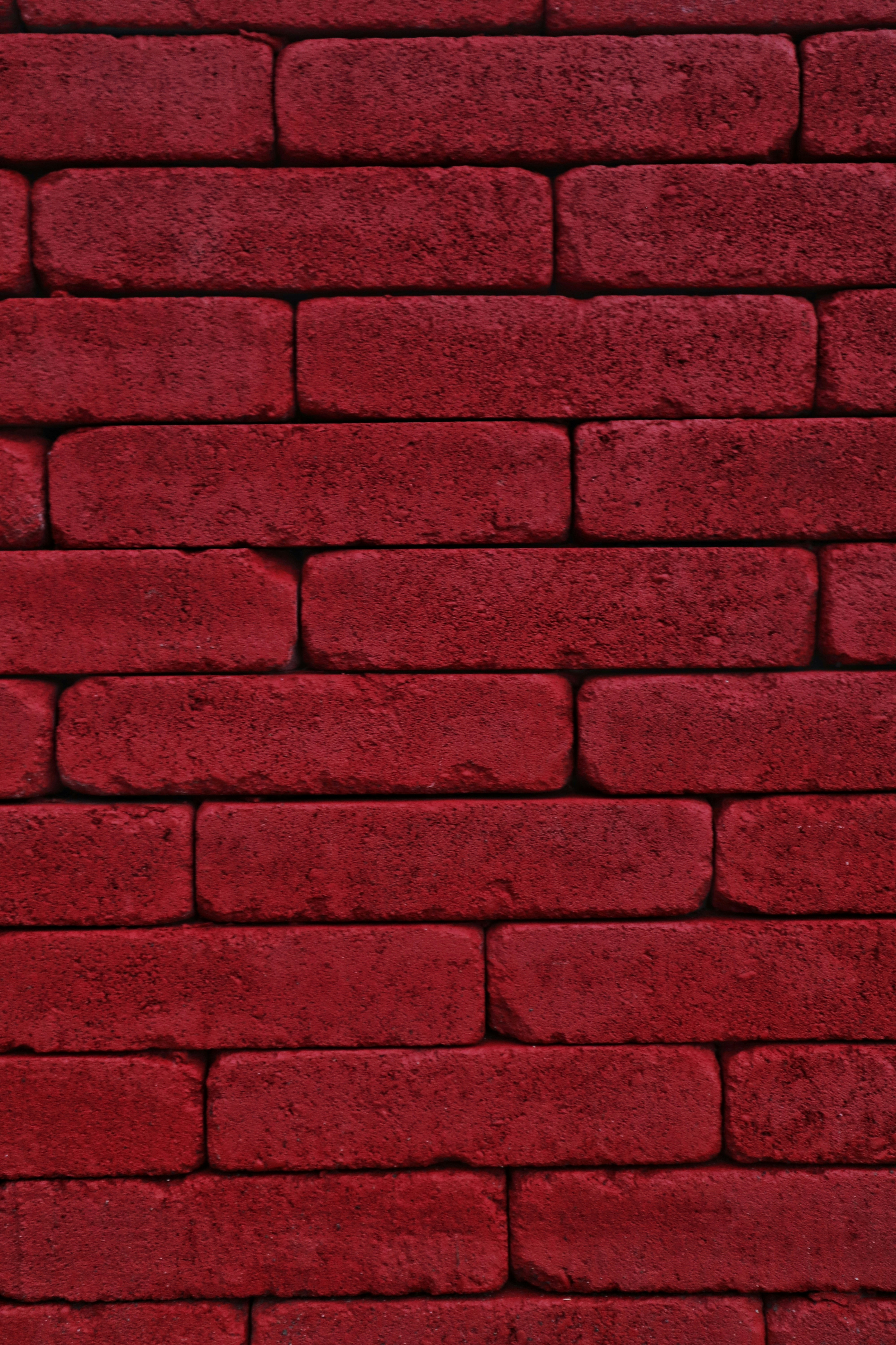 Close-up of a wall made of red bricks with rough texture stacked in a horizontal pattern.