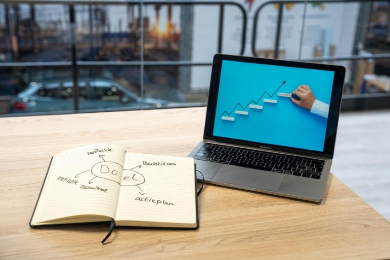 Notitieboek met doel, motivatie en actieplan naast een laptop