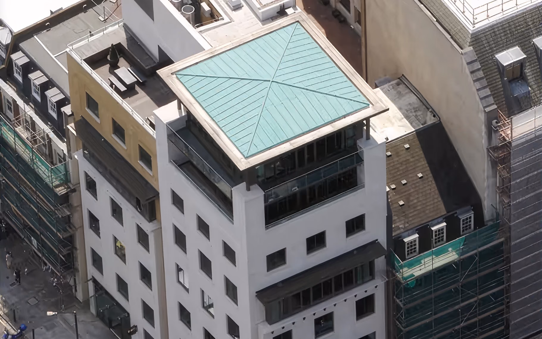 Aerial view of a white multi-story building with a green pyramid-shaped roof on top.