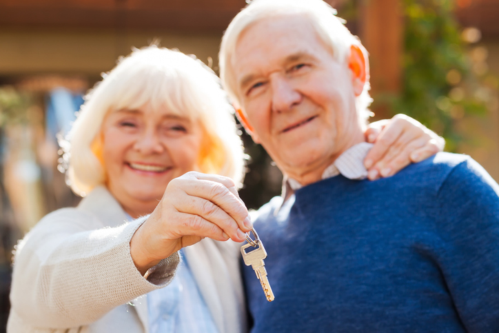 An older couple holding a key to their new home.