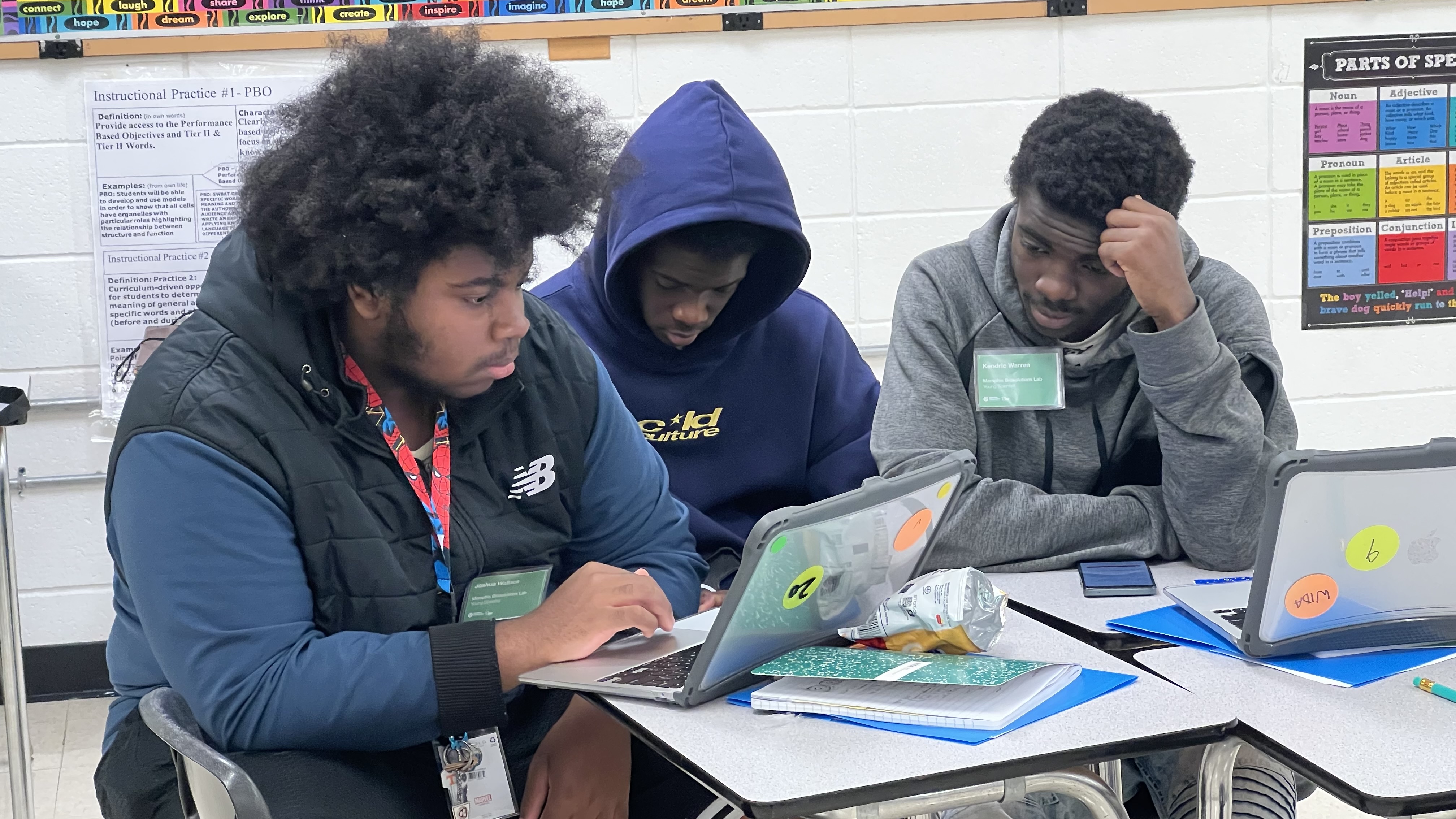Three young scientists collaborating at a laptop to design a prototype of their biosolution