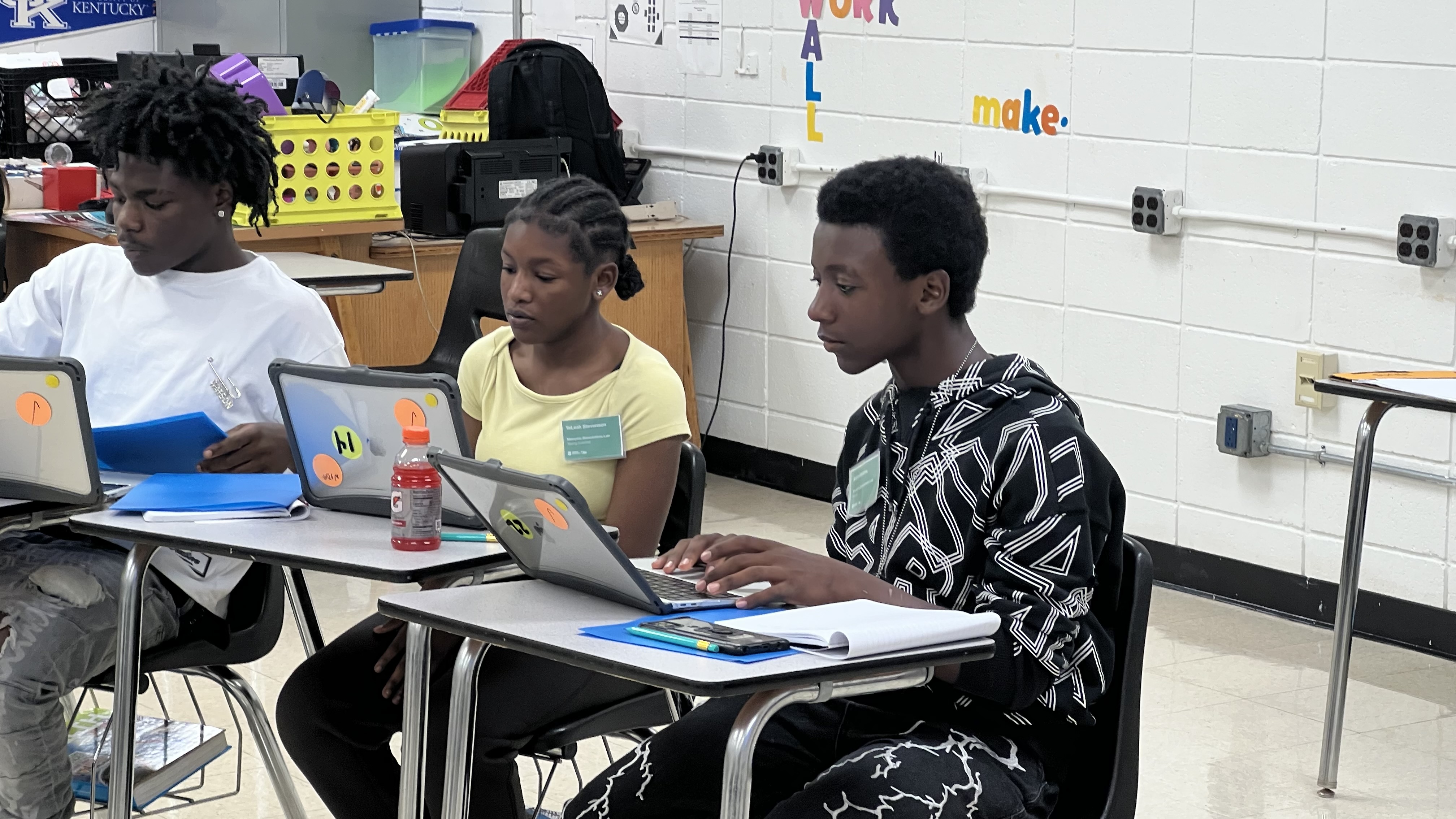 Three young scientists at desks researching a pollution problem in Memphis on their laptops