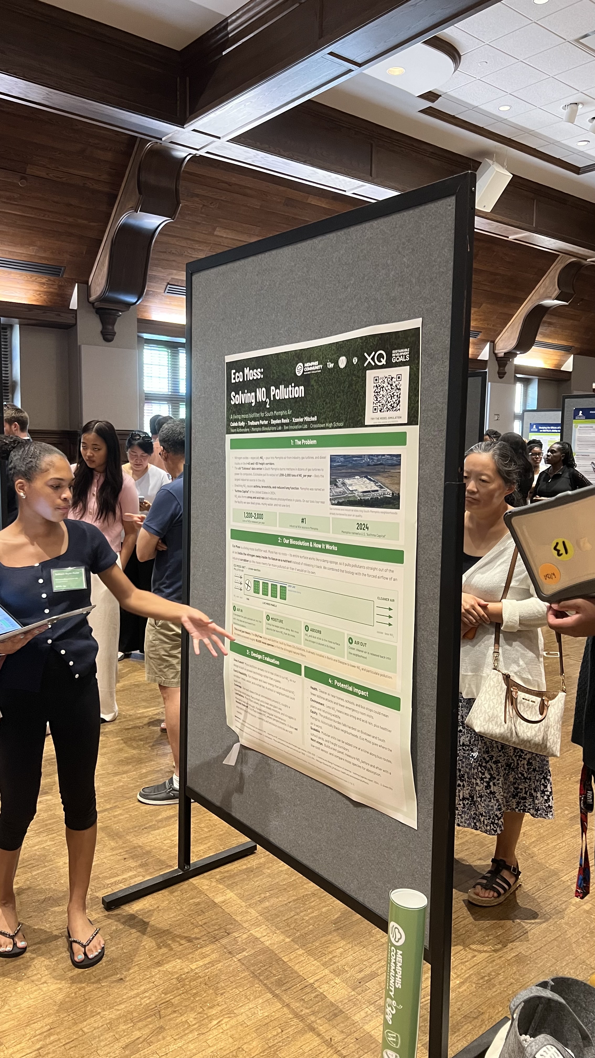 A young scientist presenting her poster on Eco Moss, a biofilter designed to solve nitrogen dioxide air pollution