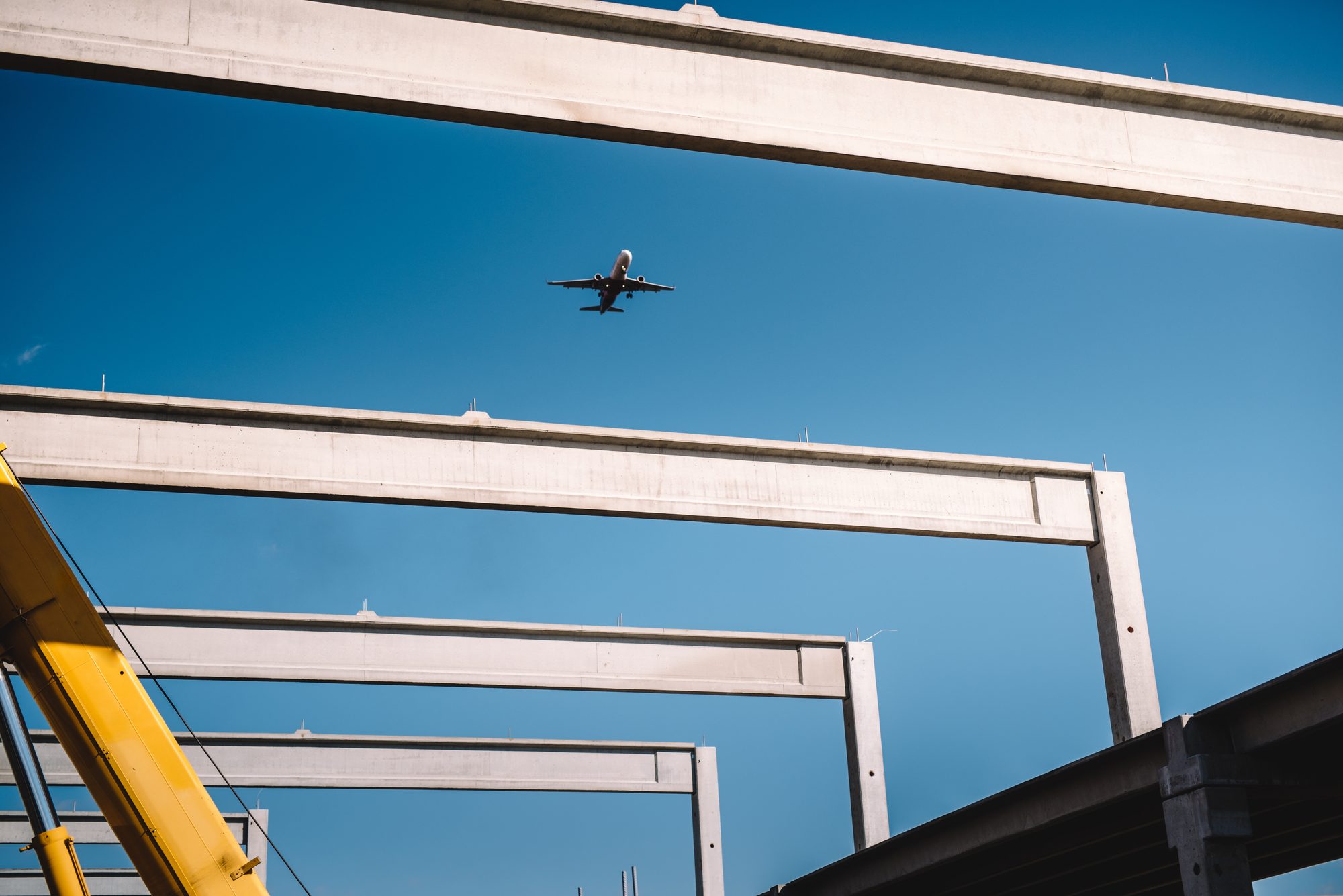 Concrete beams on a construction site with a plane overhead