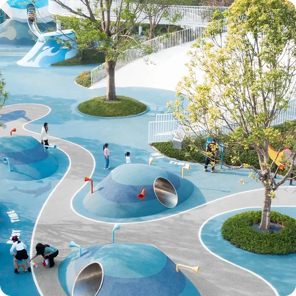 Blue outdoor play landscape with tunnels, paths, trees, and interactive features