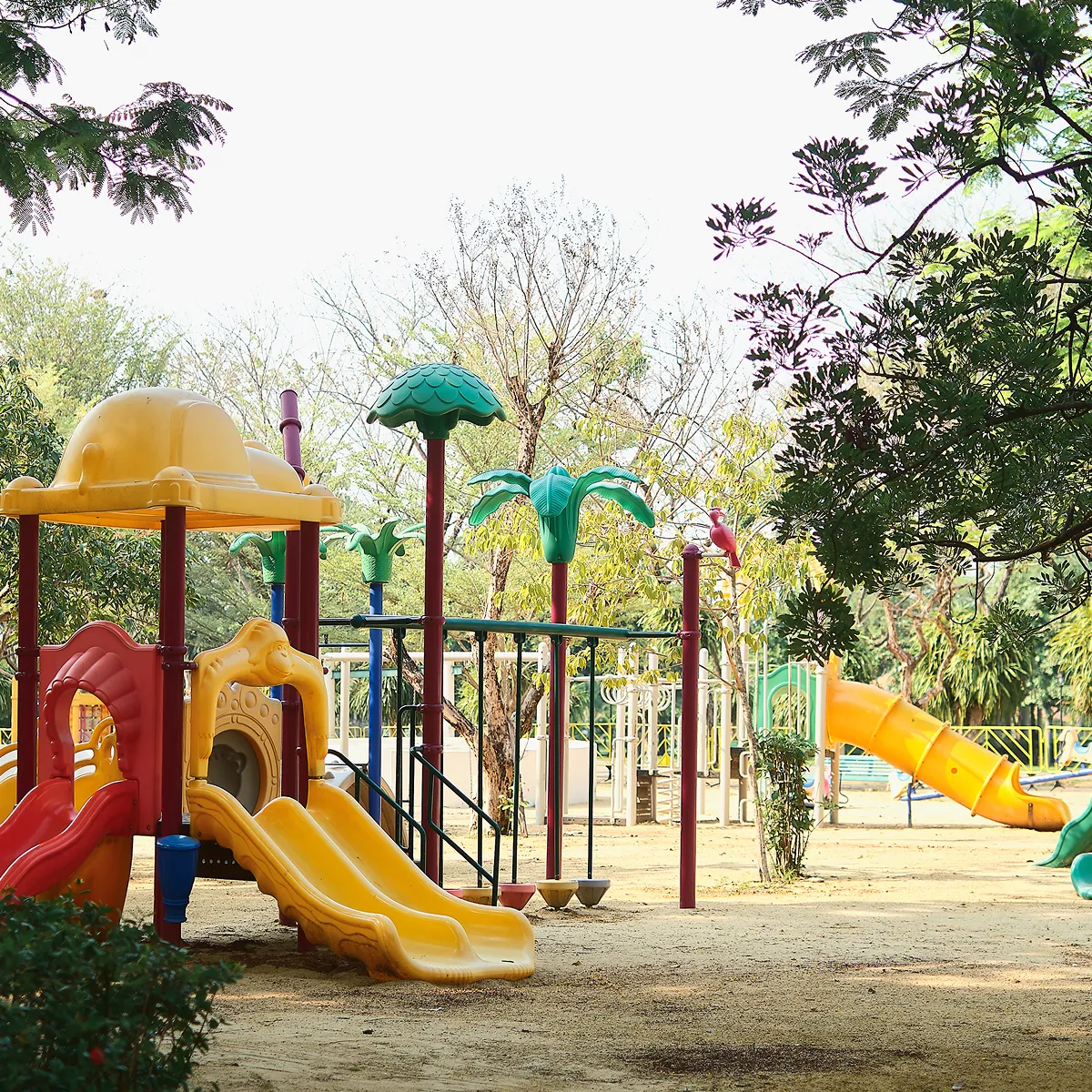 Outdoor playground with colorful slides, climbing structures, and trees