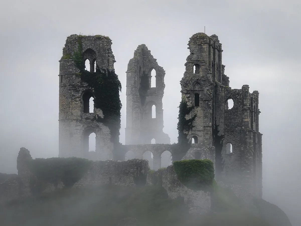 Ancient castle emerging through mist in a dramatic atmospheric landscape.