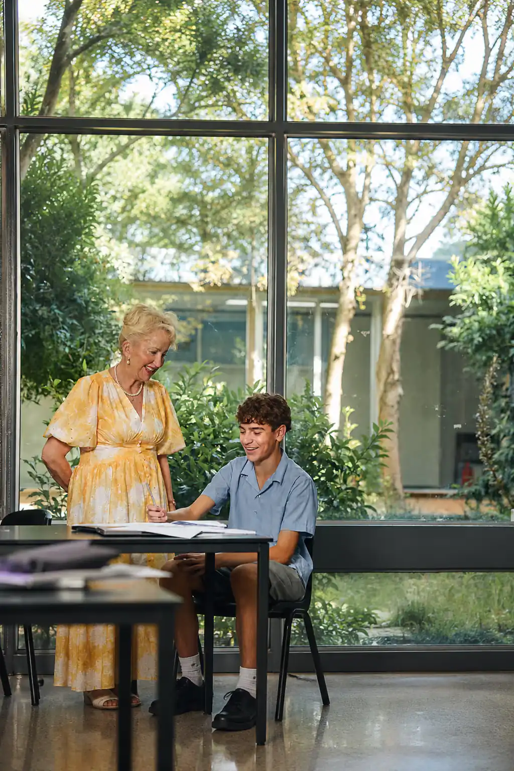 A teacher supporting a secondary school student at a desk
