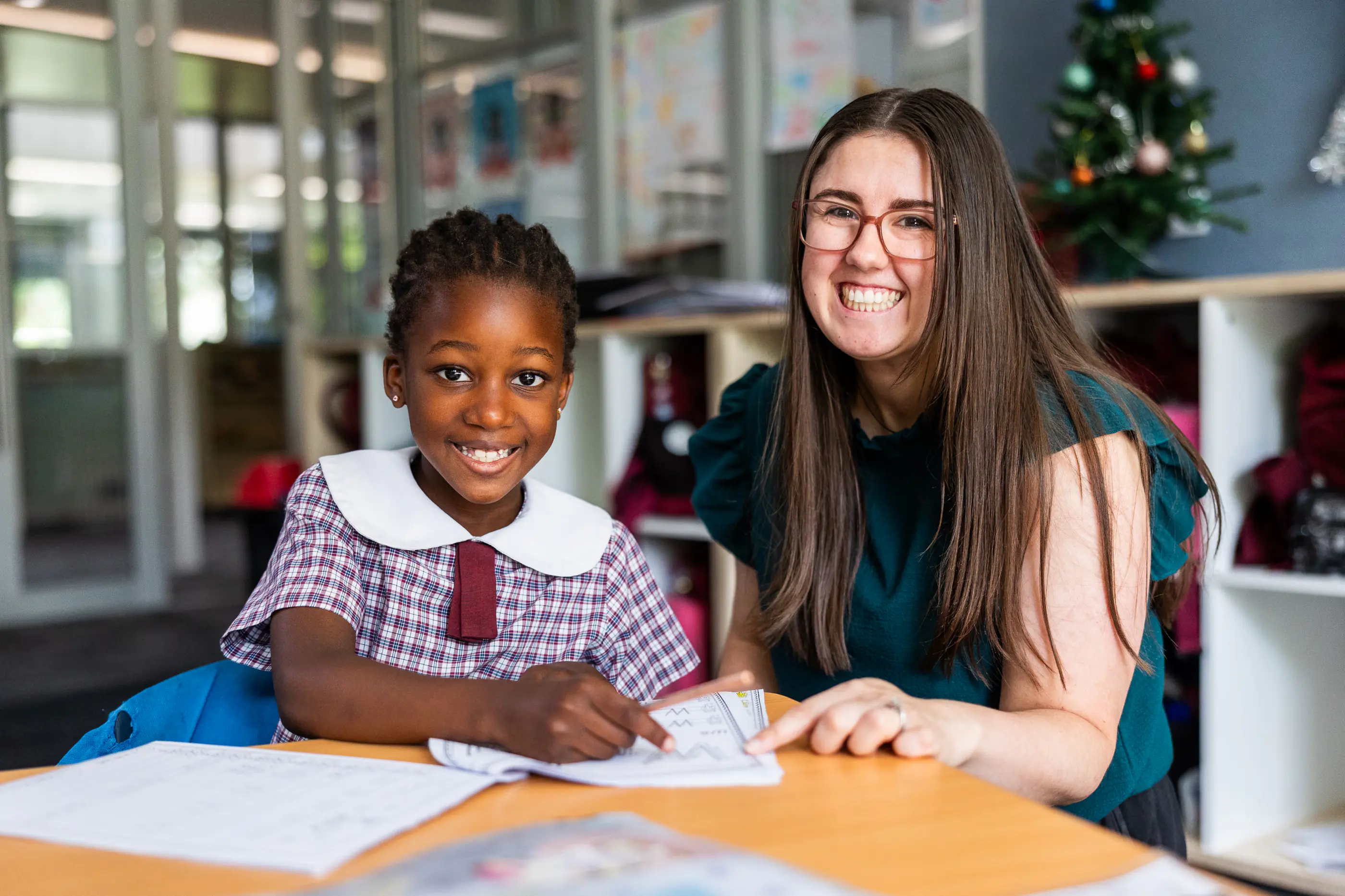 A teacher and primary school student smiling together in a classroom